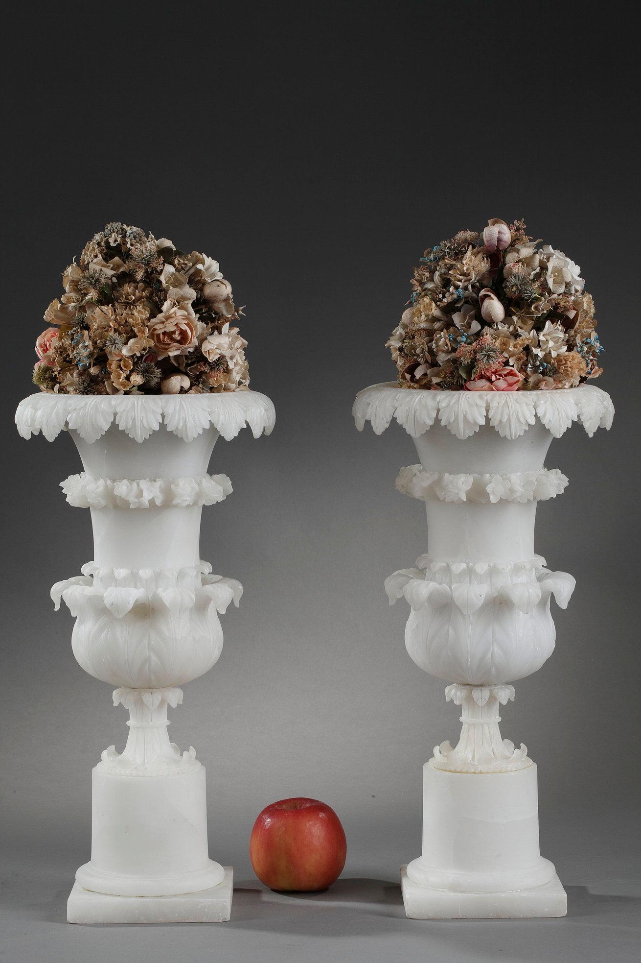 Pair of alabaster Medici vases with foliage from the Charles X period. The lip and the heel are underlined by foliage. The neck is decorated with a border of flowers. each of the vases rests on a cylindric base. 

This long and flared shape comes
