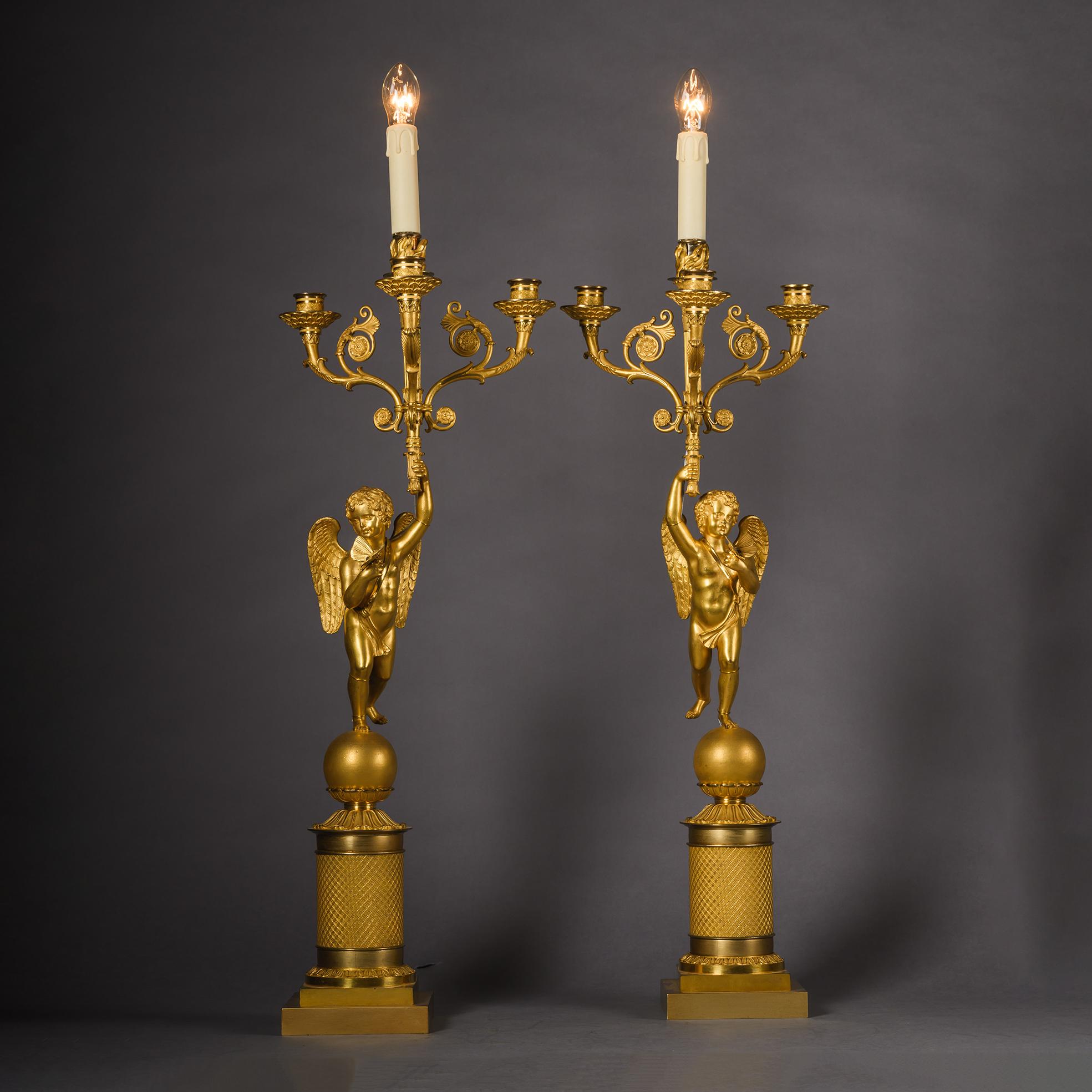 Pareja de candelabros figurados de bronce dorado Charles X, equipados como lámparas.

Cada una está modelada con una figura de cupido sobre una esfera con una mariposa en una mano y sosteniendo en alto un candelabro con tres boquillas de vela y luz