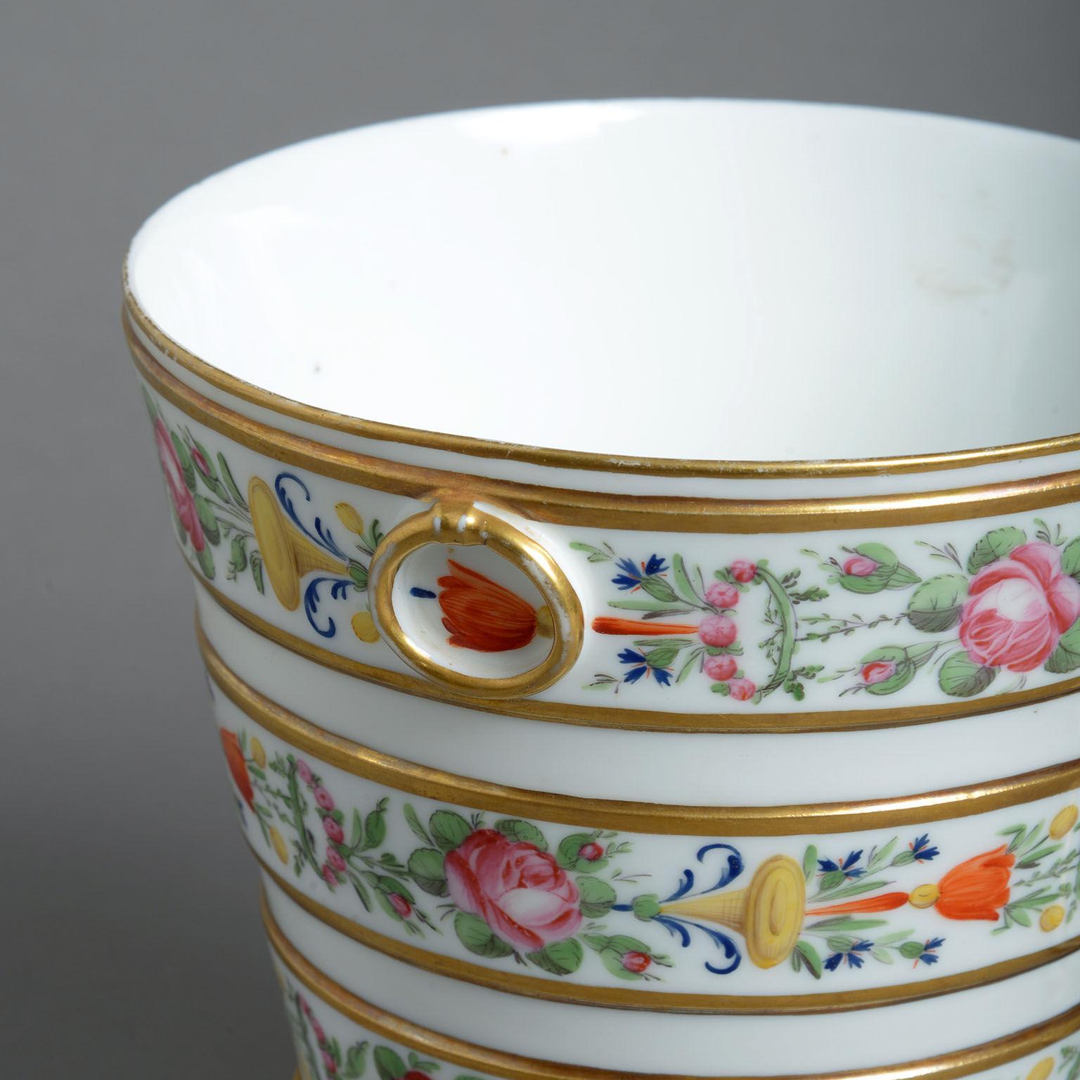 The flared forms delicately painted with bands of summer flowers within borders of gilding and with moulded loop handles.
  