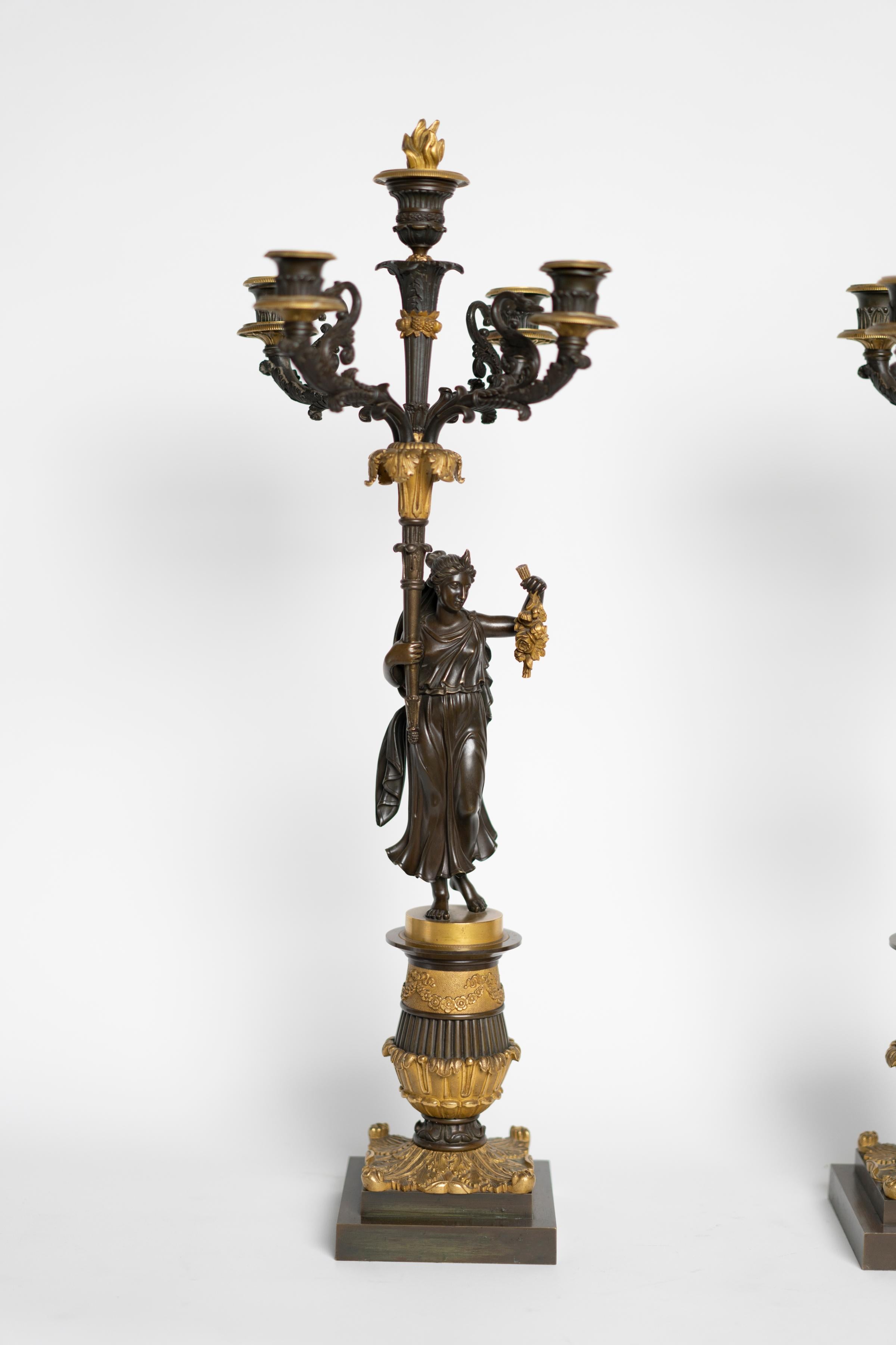 Zwei vergoldete und patinierte Bronzekandelaber aus der Zeit Karls X. mit einem römischen Paar, das vier Kerzenhalter hält.