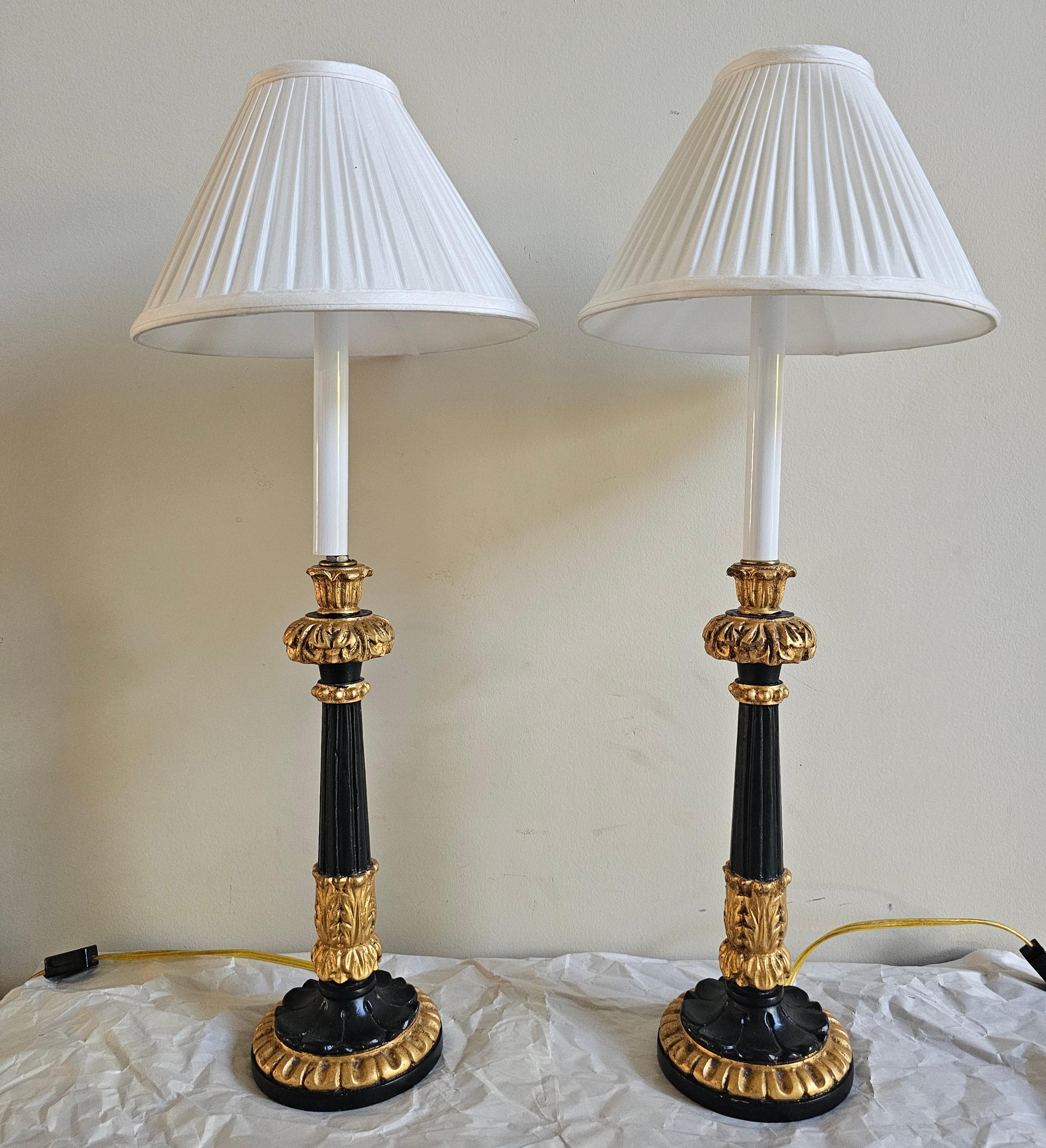 Paire de chandeliers en bois doré Charles X et en émail noir ébonisé, montés comme lampes. Mesure 5,5