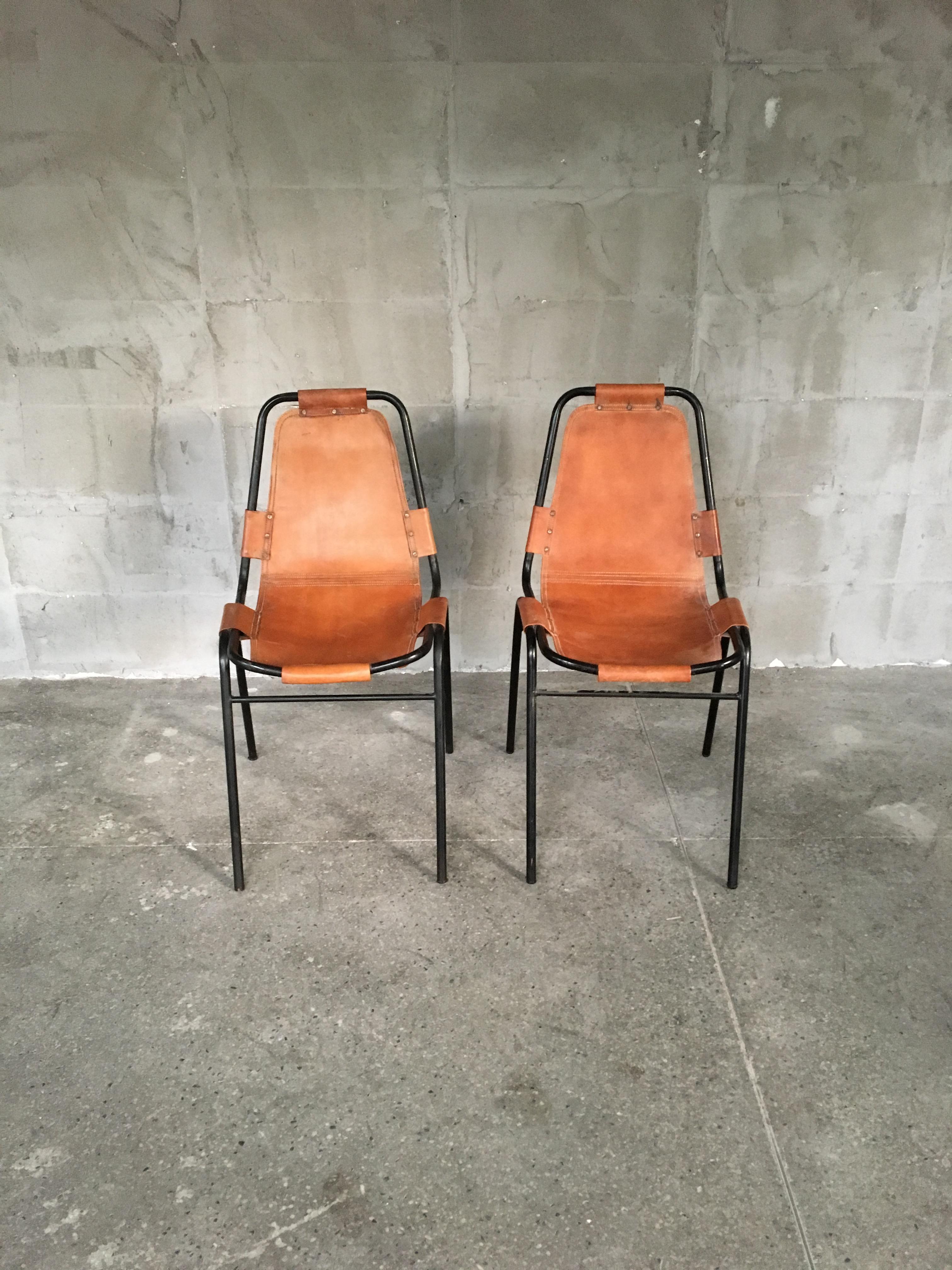 A rare pair of lovely and and especially charming chairs by the famous French designer Charlotte Perriand, made in the 1950s. The metal structure is painted in black, that is very rare and indicative sign for the 1950's, which gives them particular