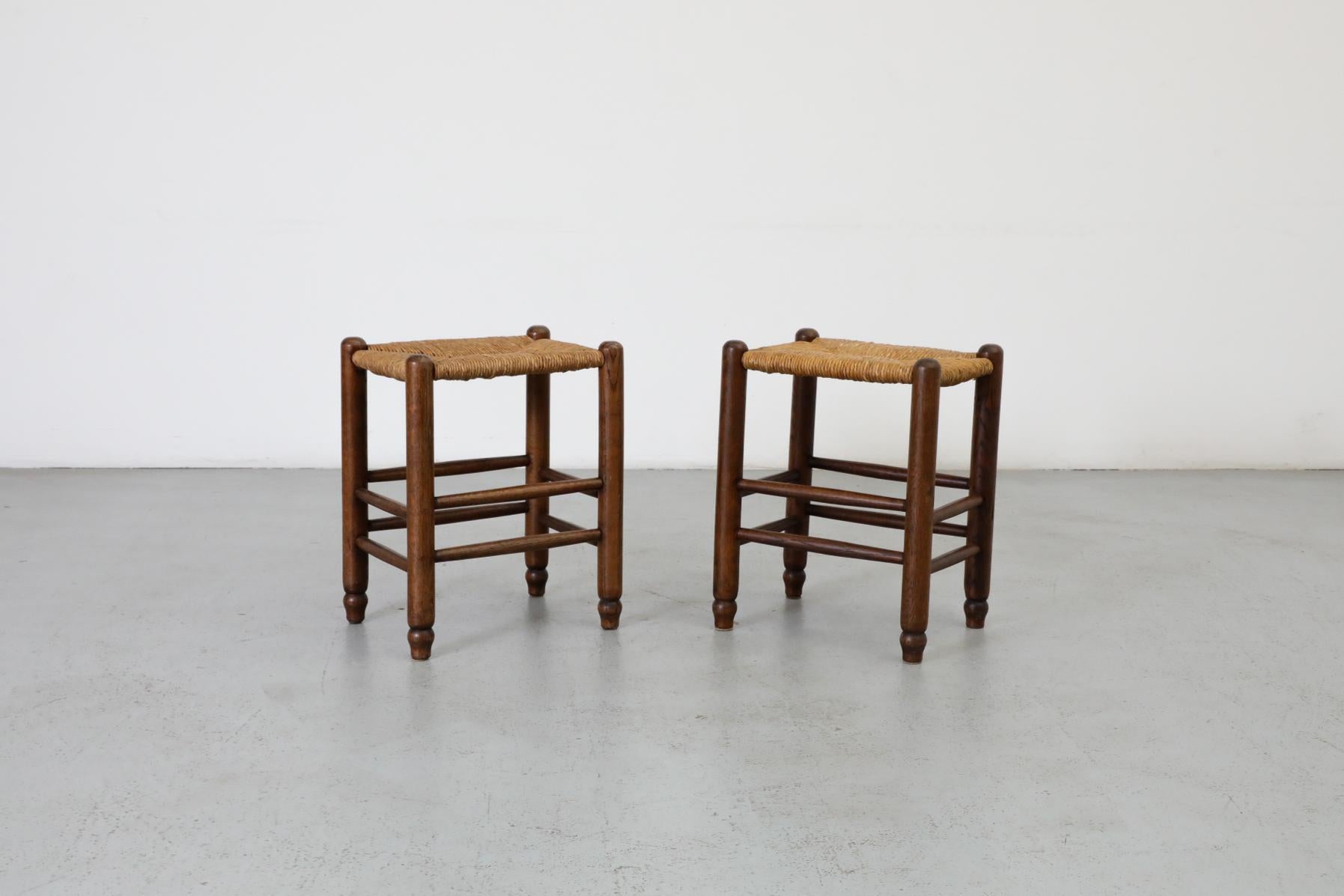 Pair of Dutch Mid-Century Charlotte Perriand style petite stools with handsome dark oak frames with turned legs and hand-woven rush seats. Designed in a style that is reminiscent of the work of design icon Charlotte Perriand. These beautiful pieces