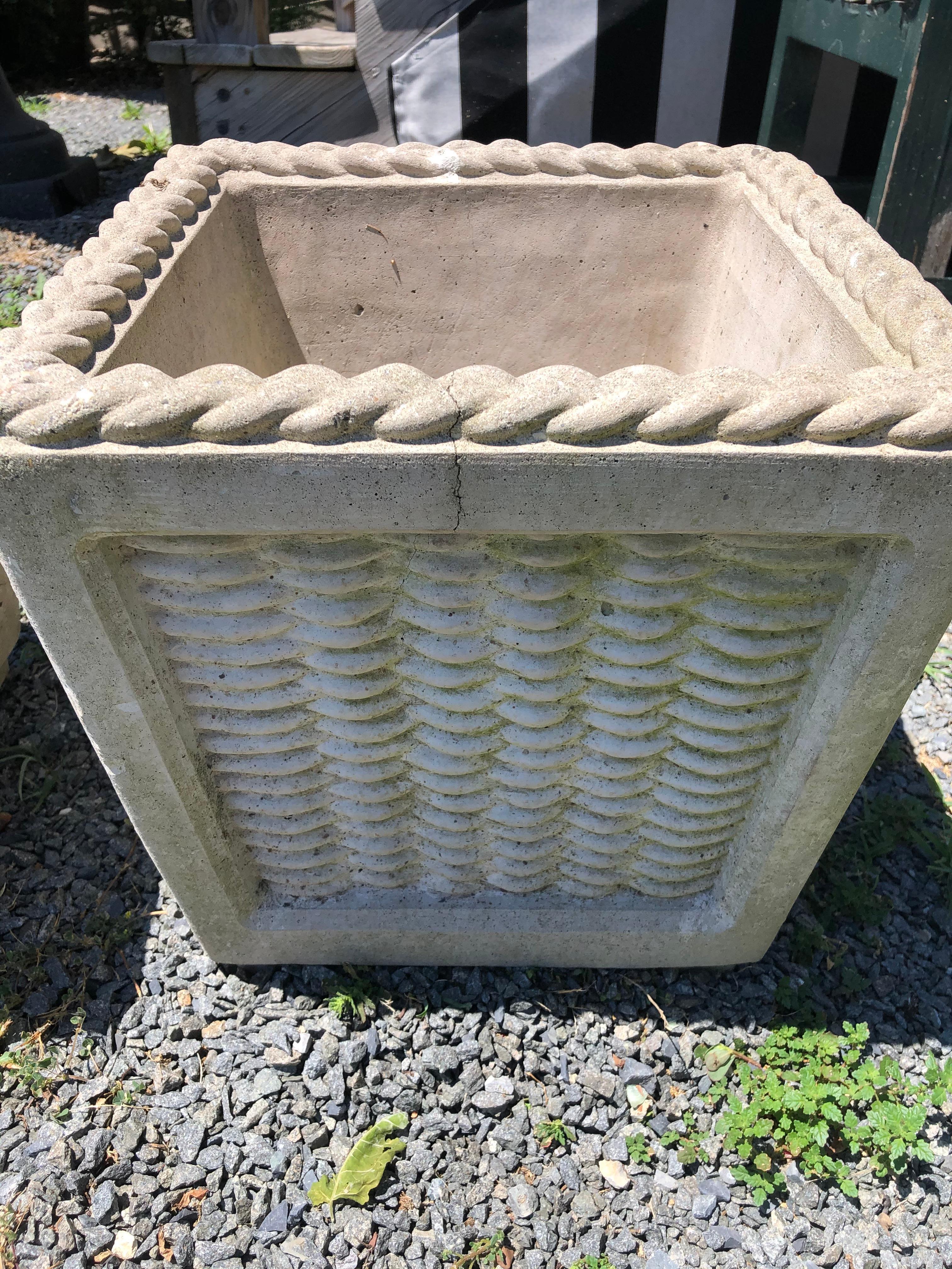 A charming pair of vintage cast cement planters in the shape of wicker baskets having decorative braiding around the top edges.