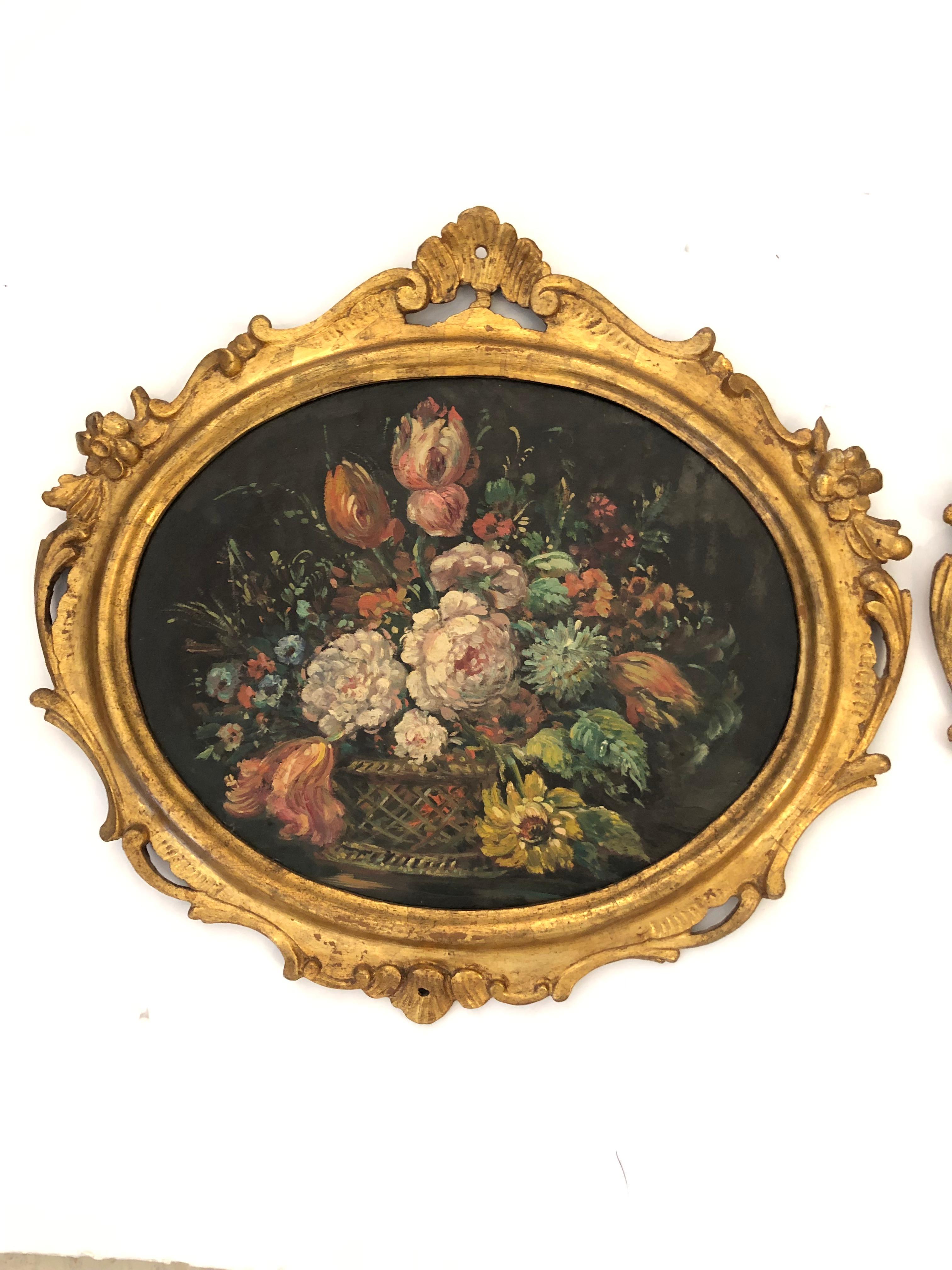 Fine pair of oval oil still life paintings on board of flower arrangements with tulips, peonies, and other garden beauties, having subtle colors against dark black background.  The giltwood carved wood frames are wonderful. 