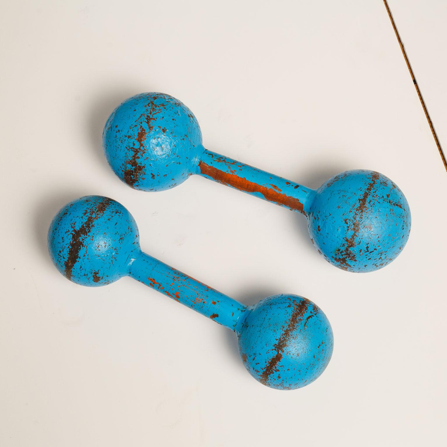 Pair of vintage iron barbells painted in cyan, or cerulean, blue. Hand-hammered with slight variations in size and proportion. Wonderfully decorative.

First barbell measures 4.75 inches high x 15.5 inches long x 4.75 deep.
Second barbell
