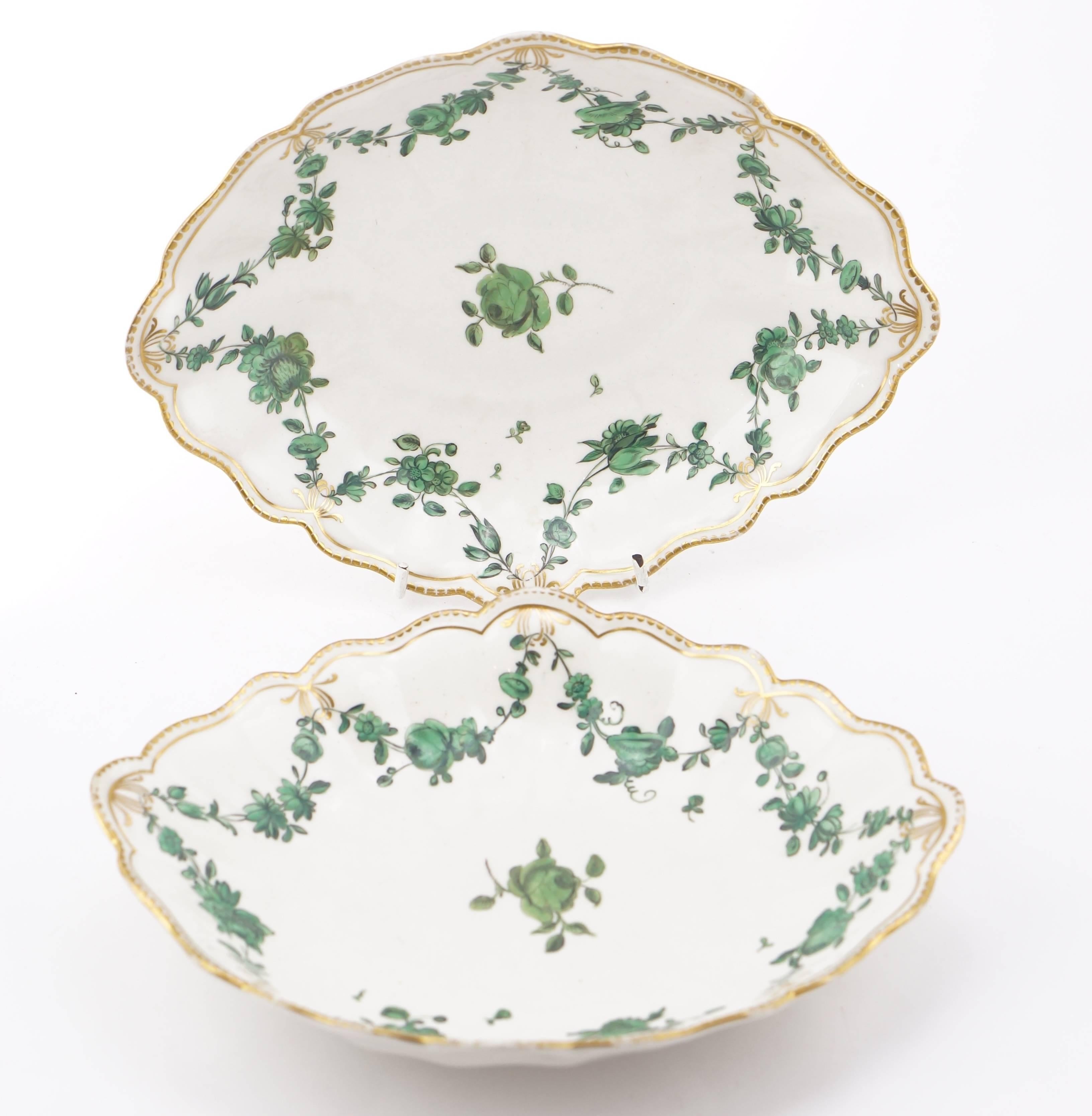 Pair of Chelsea-Derby shaped serving dishes, painted in black outlined green enamels with swags of flowers pendant from a gilt line border, the rim with a gold dentil edge. Gold anchor mark, circa 1770.