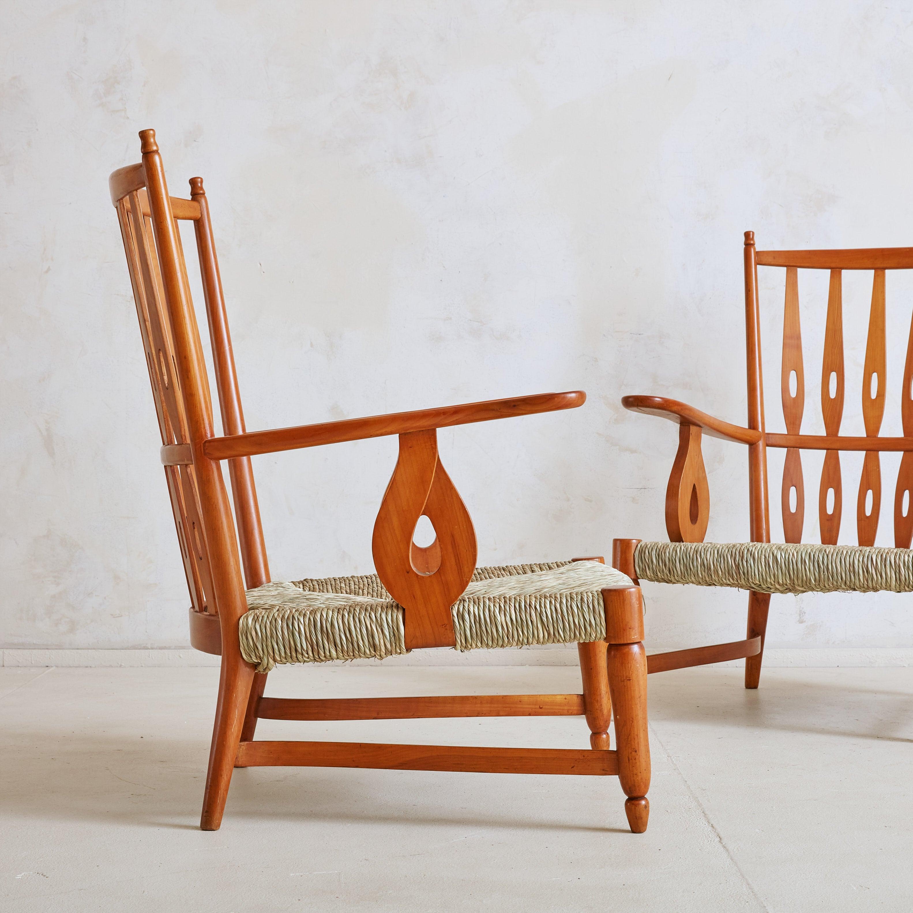 A rare pair of armchairs from Italian architect and designer Paolo Buffa in 1952. These beautifully crafted chairs are constructed of solid cherry wood and feature monumental carved frames with sculpted legs, windsor style wingbacks, and softly