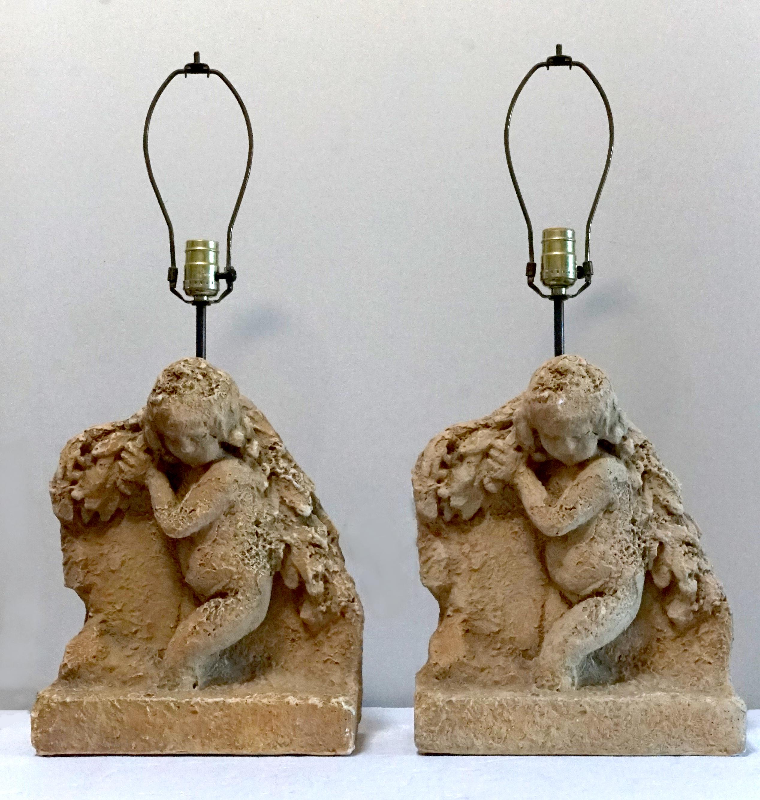 The antique look of 16th to 17th century stone or marble putti lends a classic look to these cherubic table lamps that is priceless. The lamps rest on stands with resin-cast bodies. The stands are made after coat-holding putti of the 16th or 17th