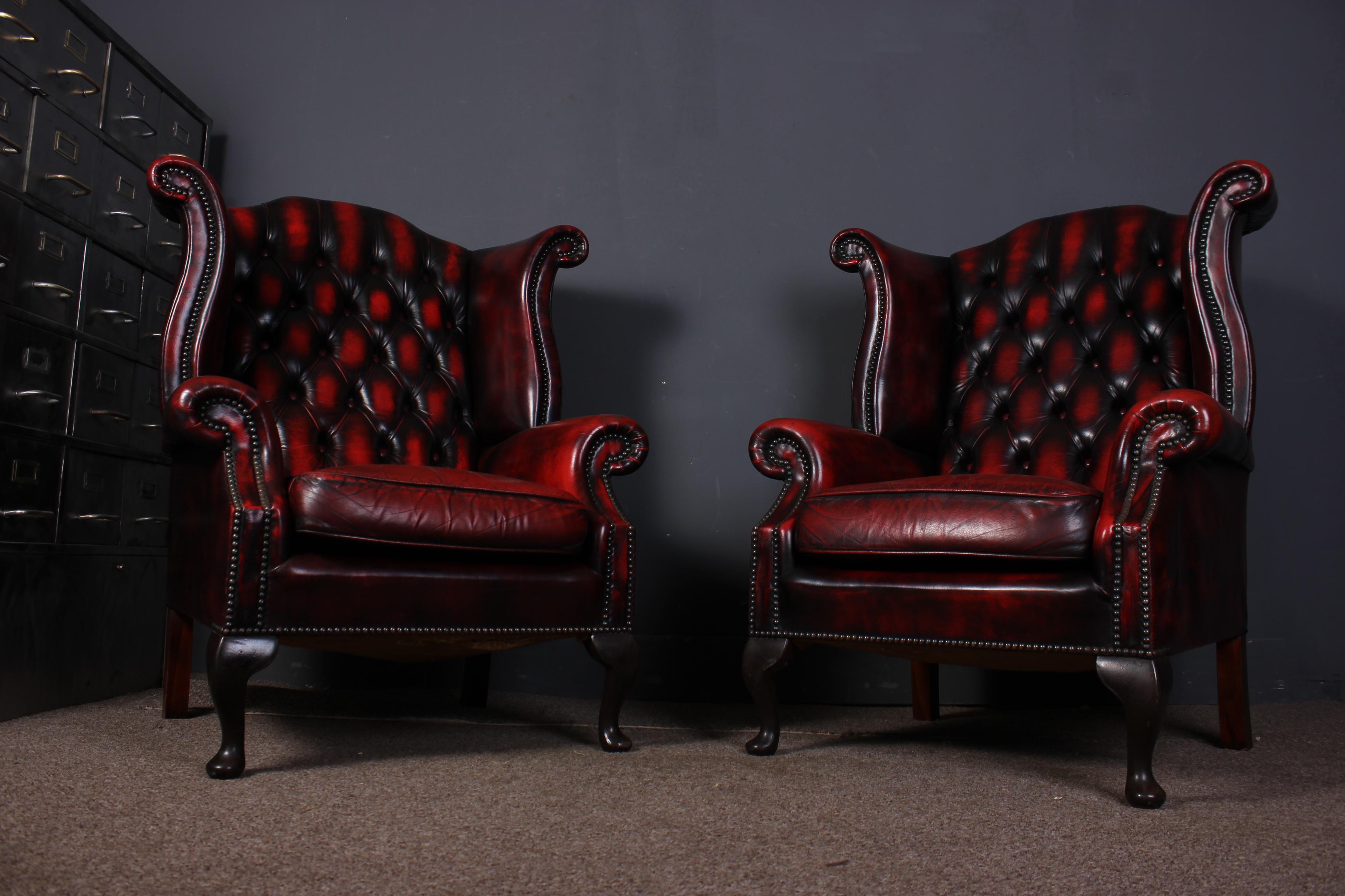 A classic pair of chesterfield Queen Anne wing chairs in a stunning oxblood red. They are in good condition with all the buttons intact but do have some minor age related marks due this does not detract from the look.

