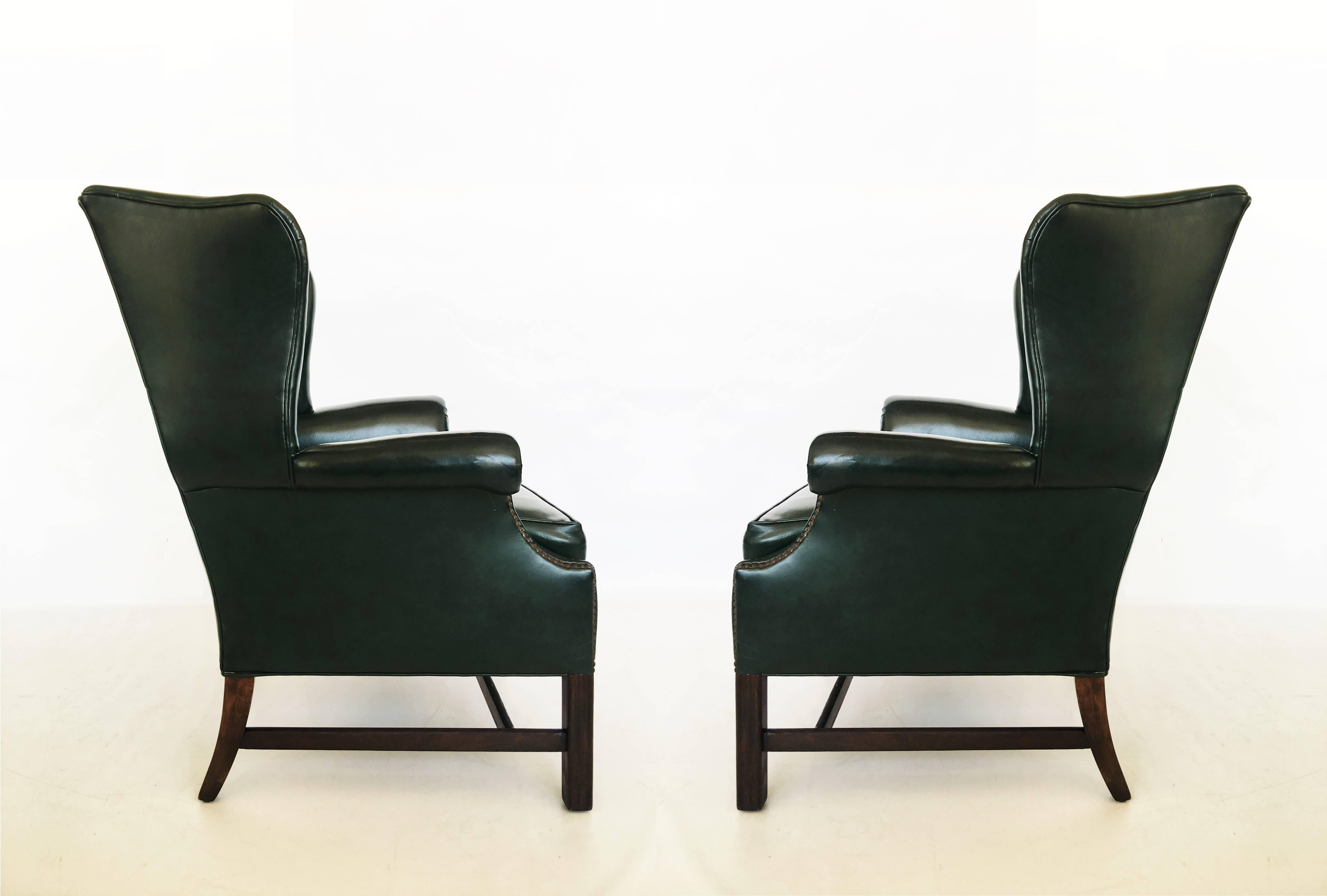 Luxurious pair of dark green deep tufted leather English Chesterfield chairs. With Classic high upholstered wingback frames. Featuring domed crest, shaped wings, a loose cushioned seat and out scrolled arms flanking button back on bead-and-channel