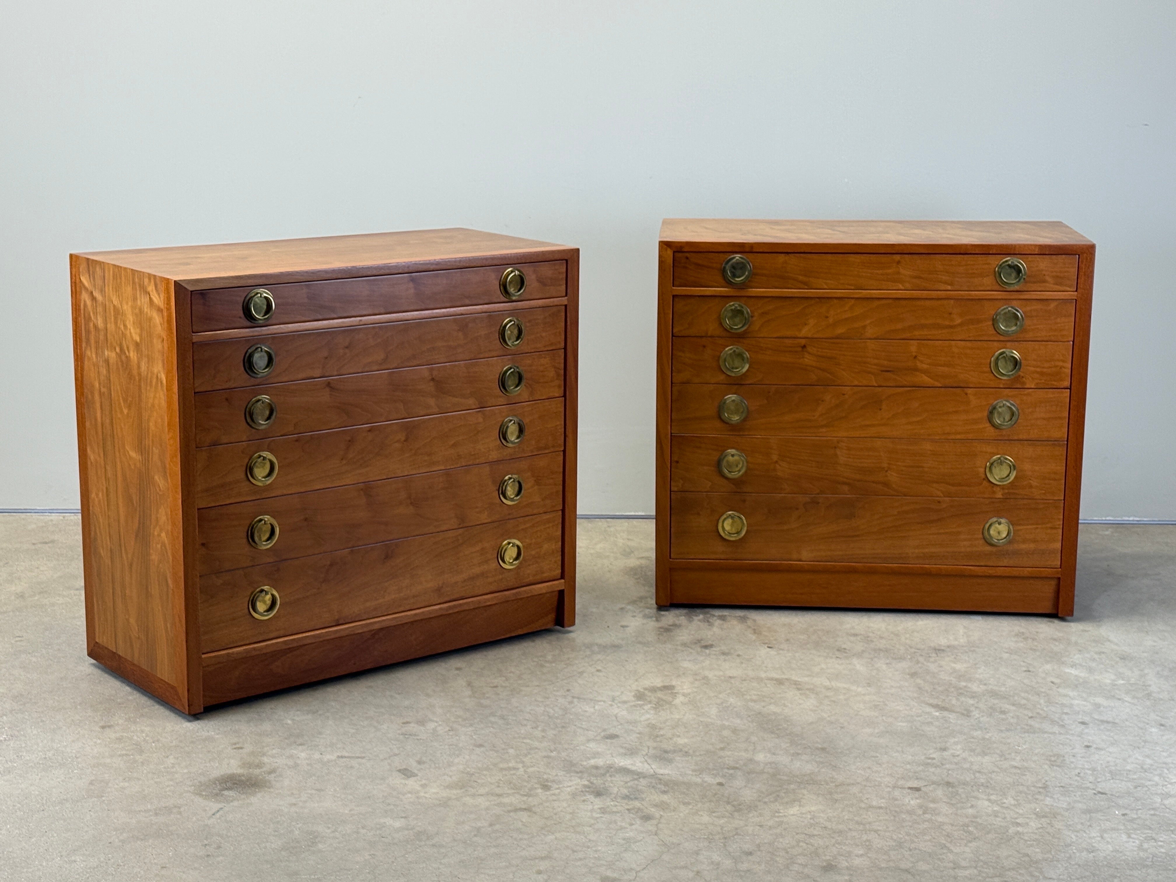 A pair of beautifully restored walnut and mahogany dressers with brass hardware. Designed by Edward Wormley for Dunbar.  