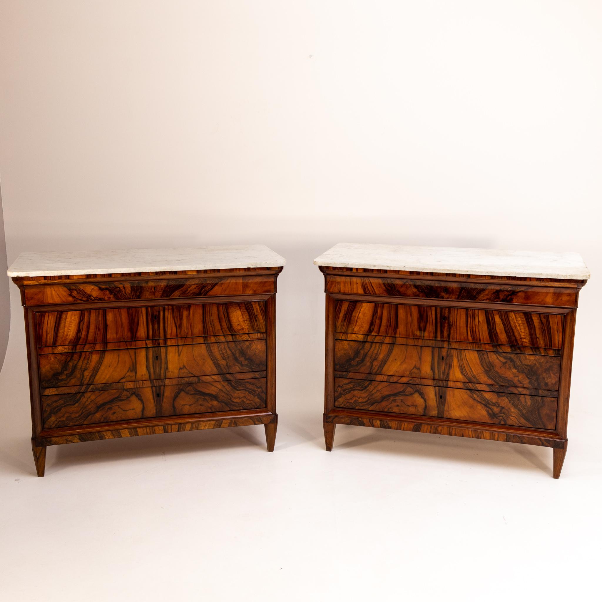 Pair of large chests of drawers with original white marble tops and four drawers. The body is veneered in walnut and has been professionally refurbished.