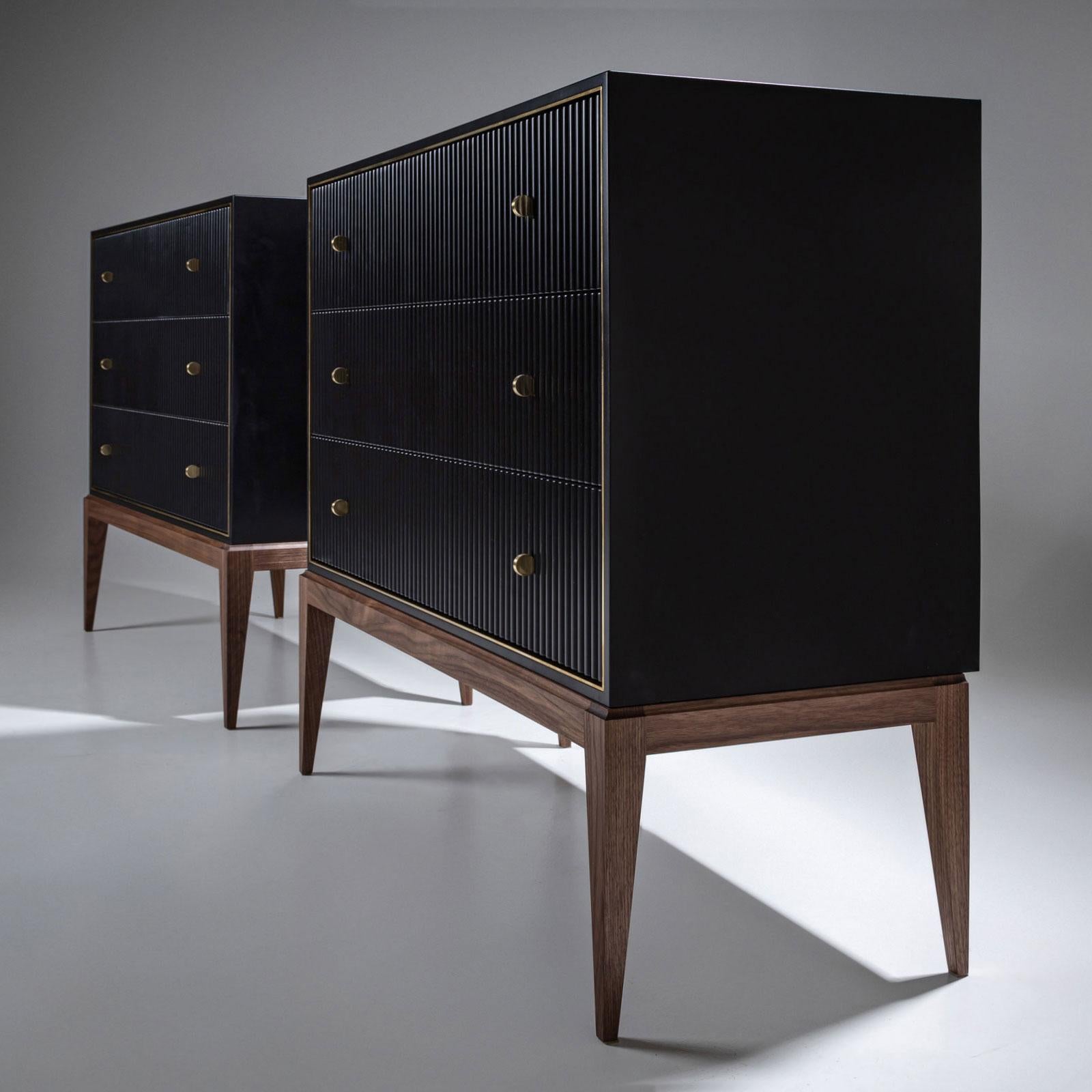 Paire de commodes d'Attila Suta, fournisseur de la cour royale suédoise. Les commodes reposent sur d'élégants pieds effilés en noyer. Au-dessus d'eux s'élève le corps à trois tiroirs, ébonisé, avec une façade rainurée et une moulure en laiton. La