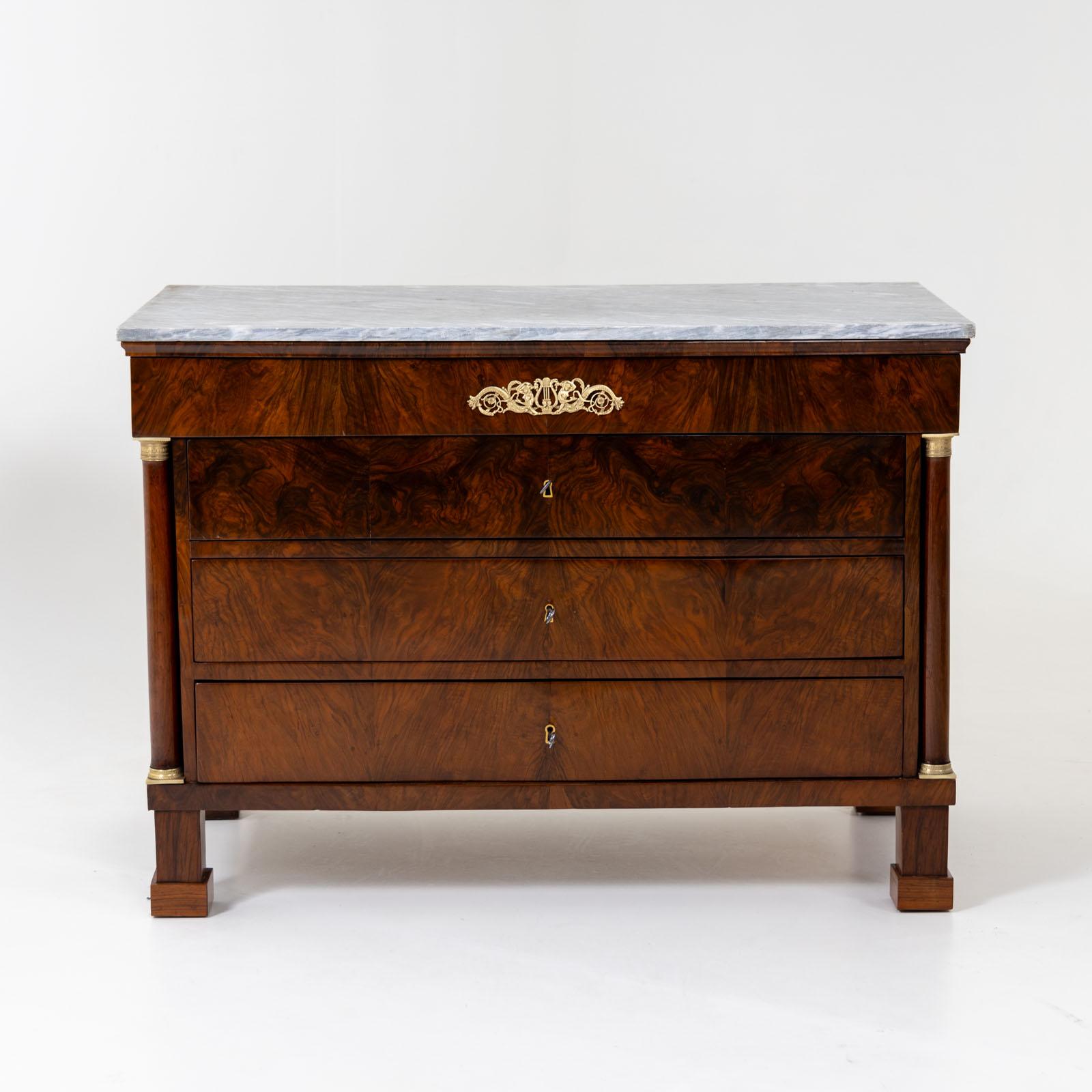 Pair of large chests of drawers with four drawers and flanking full columns with fire-gilt bronze capitals and bases. The chests of drawers are veneered in walnut and have a beautiful, dynamic veneer pattern. A light gray marble top rounds off the