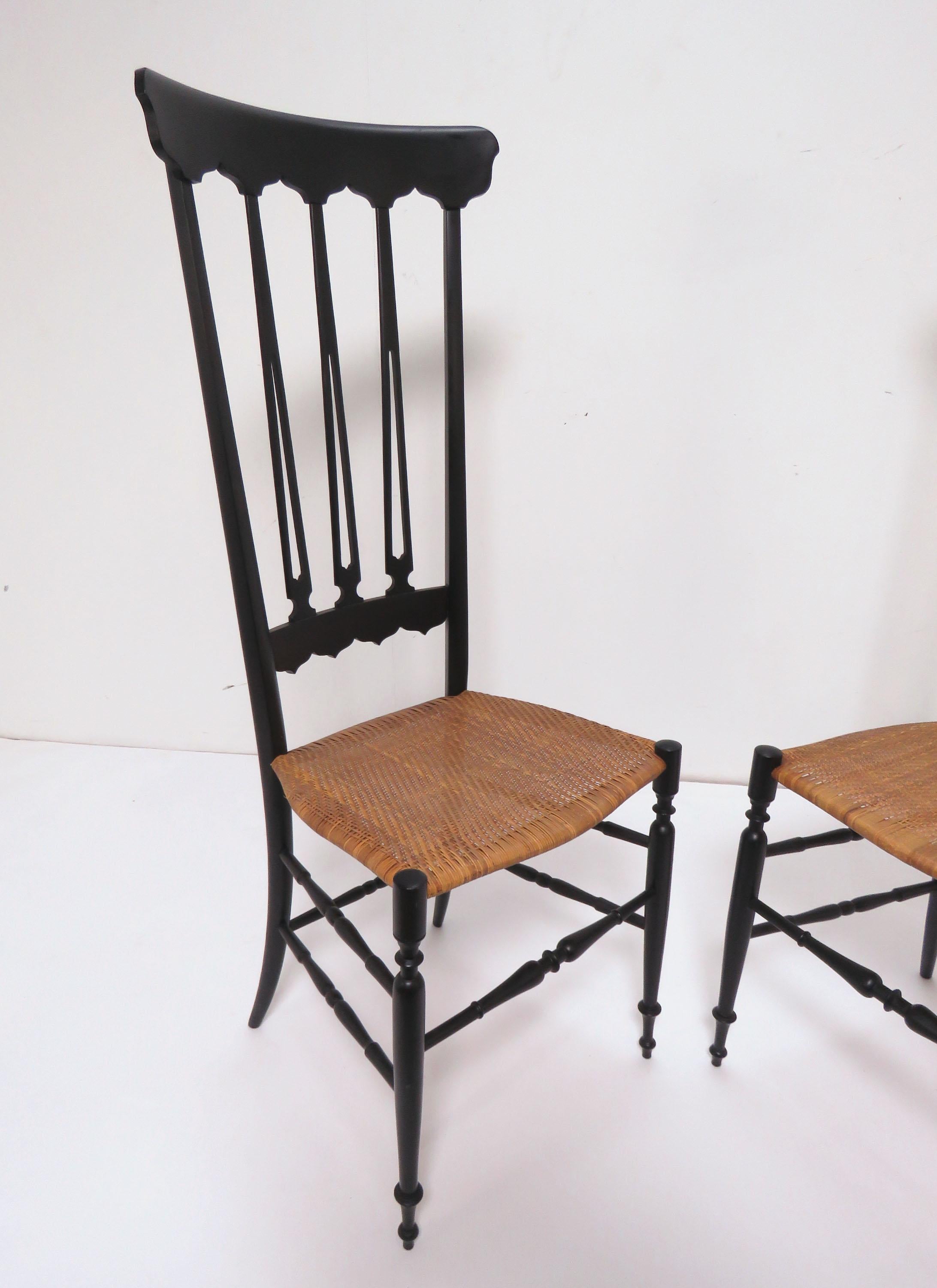 Pair of high back Chiavari chairs in original lacquer with finely carved seat backs, exquisitely turned legs and stretchers, and finely caned seats, made in Italy, circa 1960s. This style of lightweight decorative chair originated in the town of