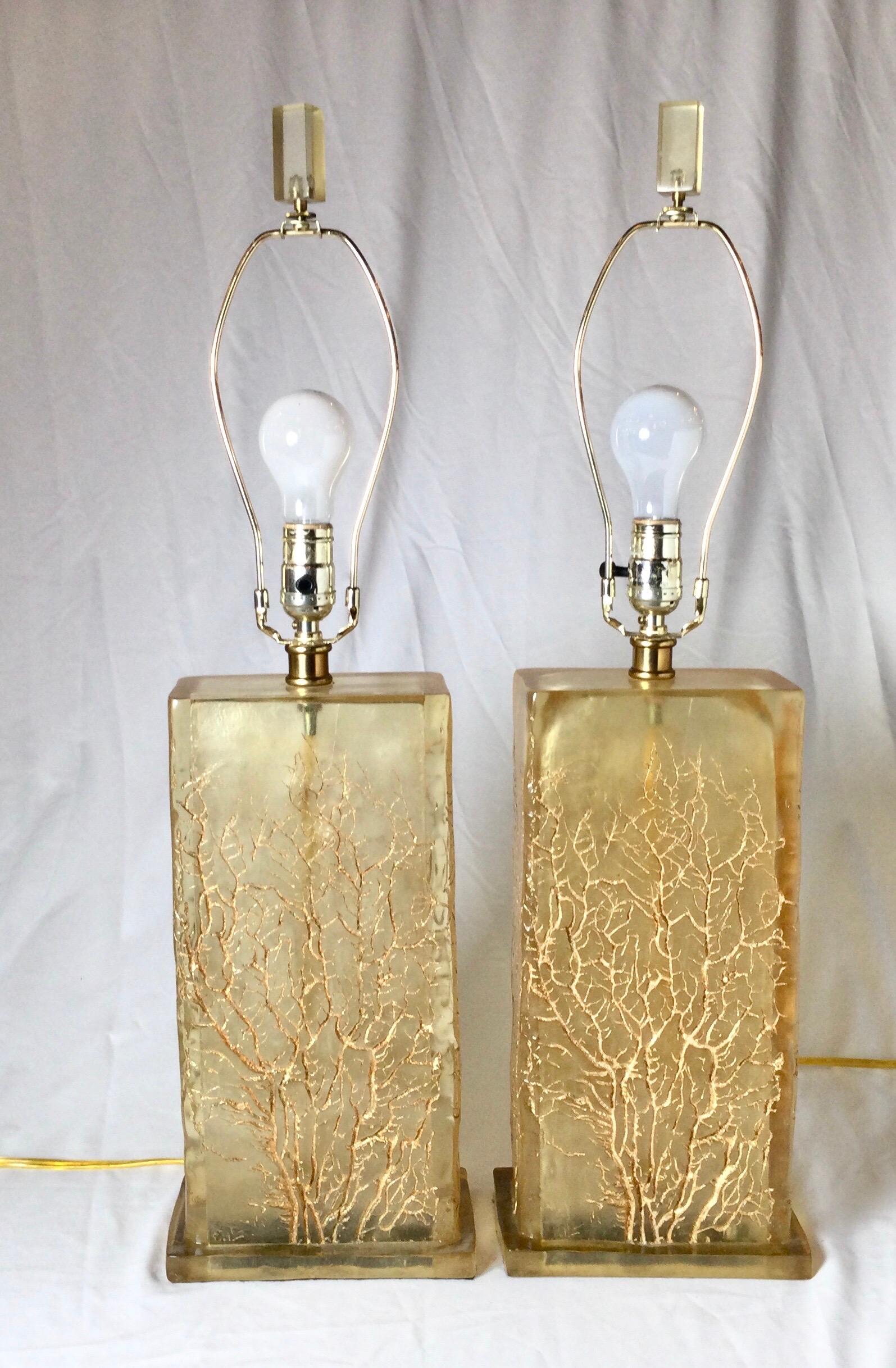 A pair of amber colored Lucite lamps with an engraved gold branch decoration. The monolith shape with each side with gold twig branch all around. The shades are for photographic purposes and not included with the lamps. 26 inches tall to the top of