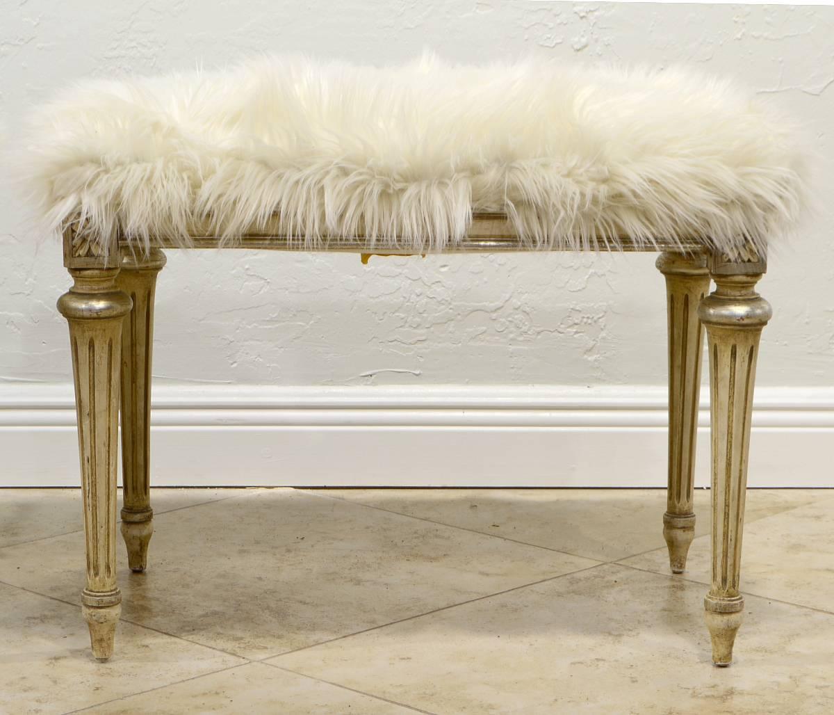 This pair of benches feature a white faux fur cover above a white painted and silver accented Louis XVI style frame with tapering fluted legs. They are retaining dated labels from Henry S. Berliner, New York.