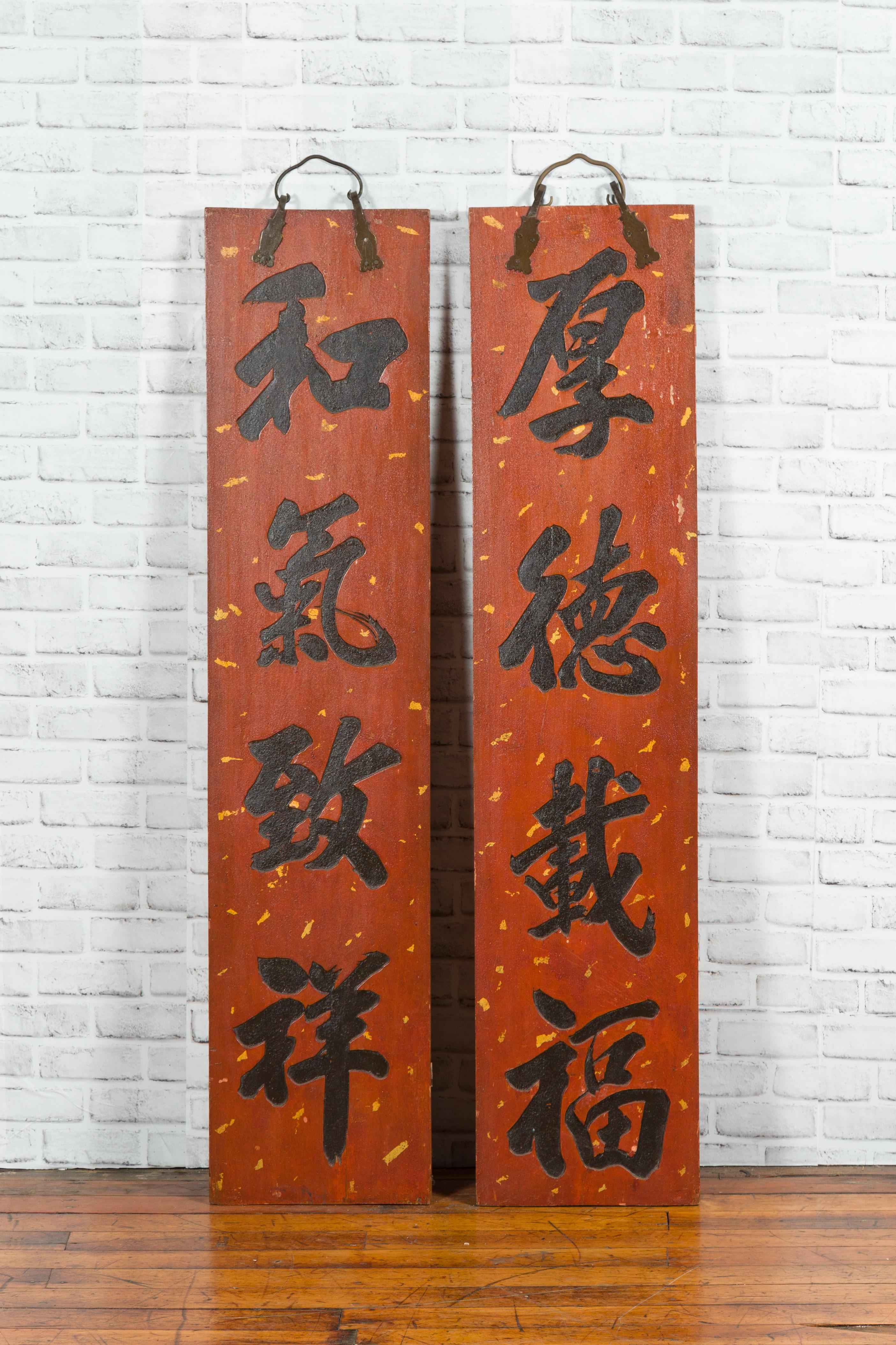 Une paire d'enseignes chinoises rouges et noires du début du 20e siècle avec calligraphie sculptée et laquée à la main. Créée en Chine au cours du premier quart du XXe siècle, cette paire de panneaux verticaux attire notre attention par sa