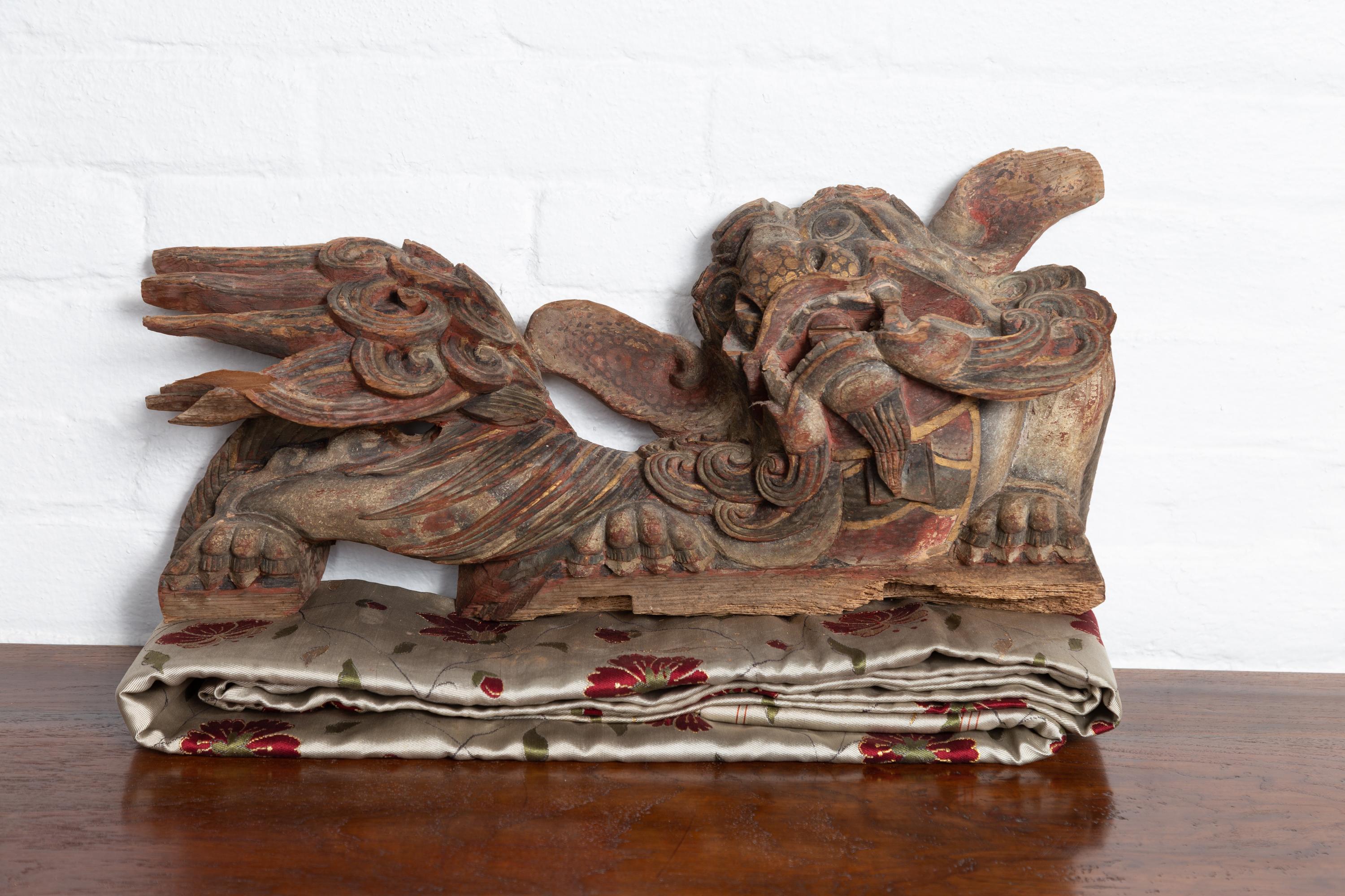 A pair of Chinese sculpted and polychromed temple guardian lions architectural wood carvings. Born in China during the 18th or 19th century, each of this pair of temple carvings depicts a hand carved guardian lion, facing left and right. Mesmerizing