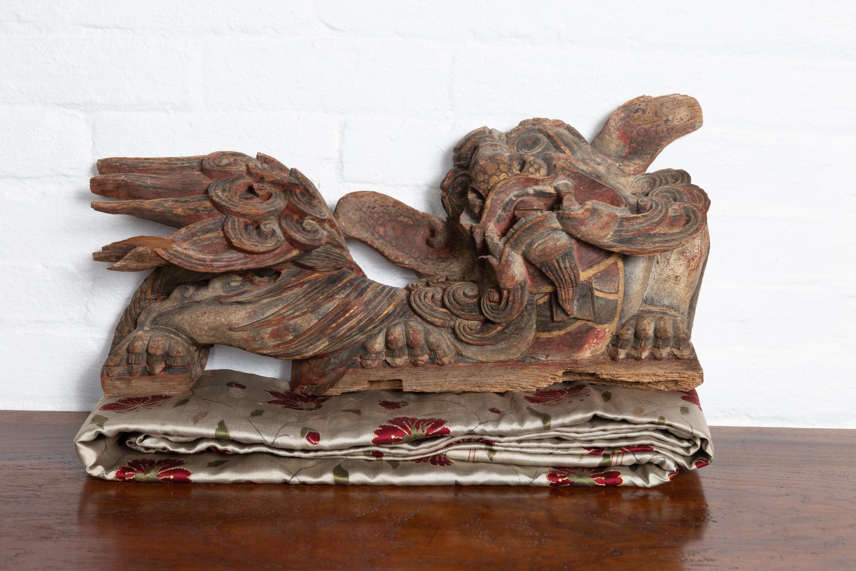 Pareja de tallas arquitectónicas chinas de madera esculpida y policromada de leones guardianes de templos. Nacidas en China durante los siglos XVIII o XIX, cada una de este par de tallas de templo representa un león guardián tallado a mano, mirando