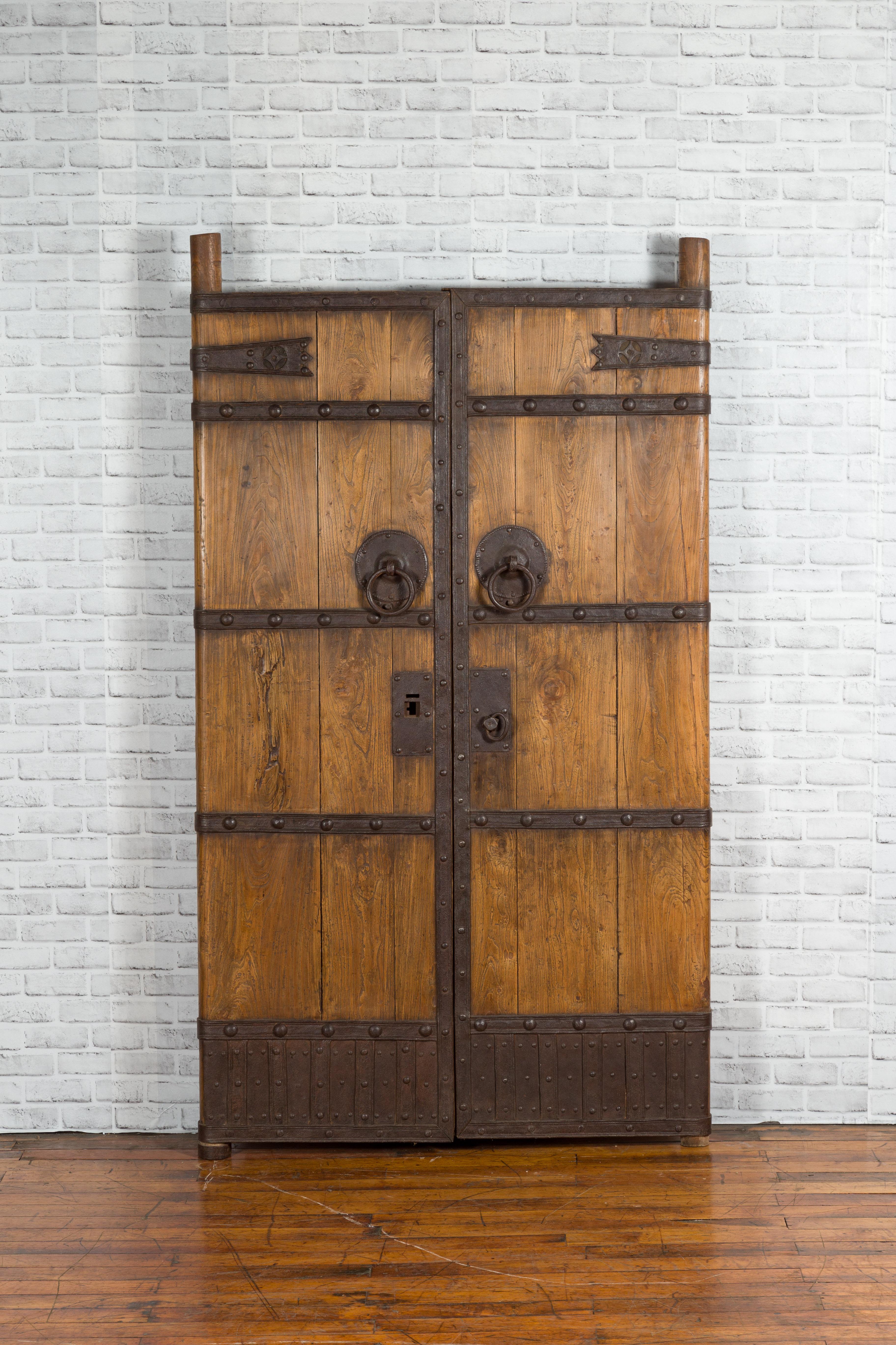 A pair of Chinese Qing Dynasty period wooden palace doors from the 19th century with iron fittings. Created in China during the Qing Dynasty, this pair of palace doors will make for a real statement! Presenting vertical slats strengthened with iron