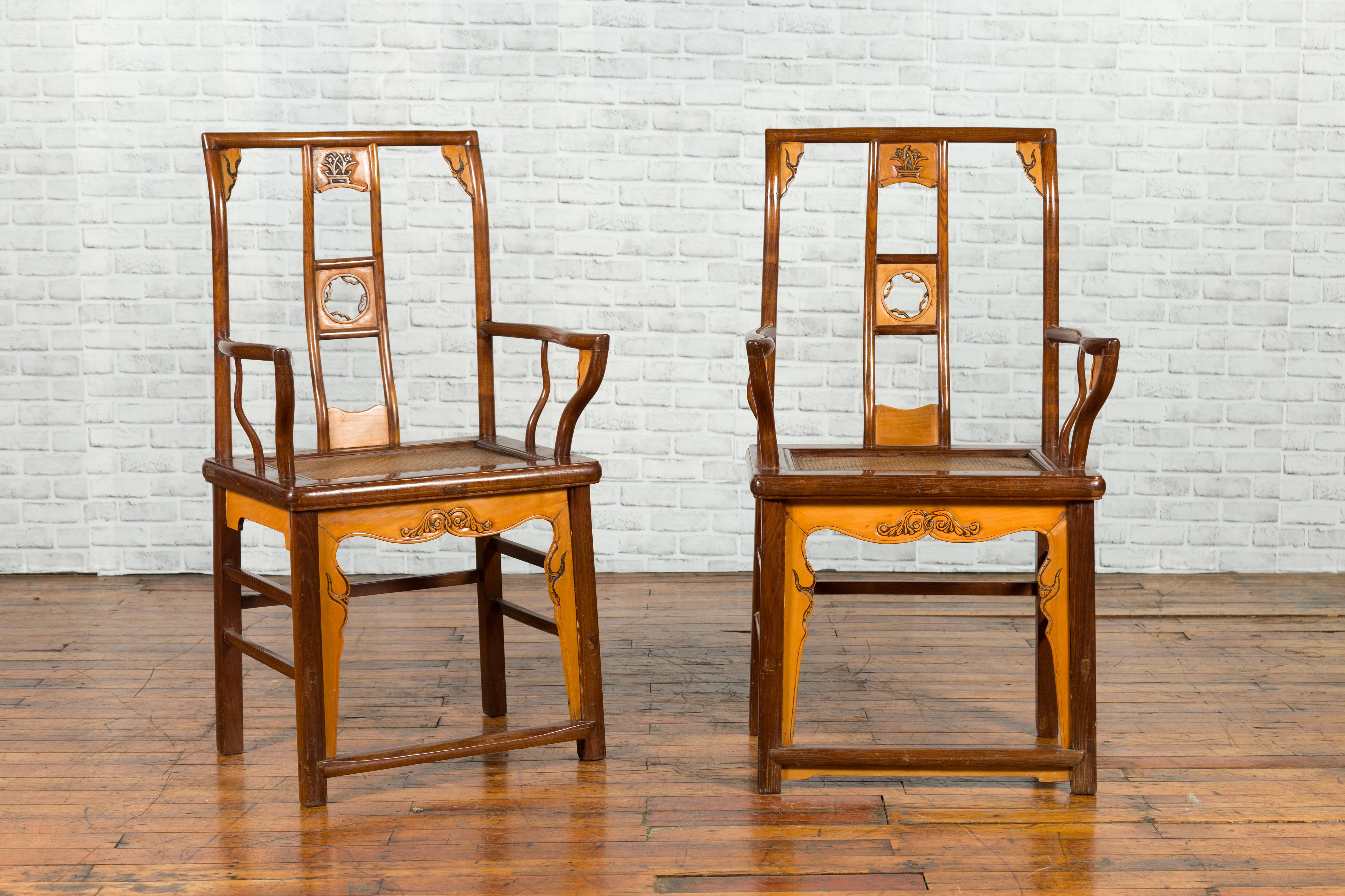 A pair of Chinese antique elm and fruitwood yoke back armchairs from the early 20th century, with pierced splats, brown patina, serpentine arms and carved apron. Created in China, each of this pair of armchairs features a tall back, adorned with a