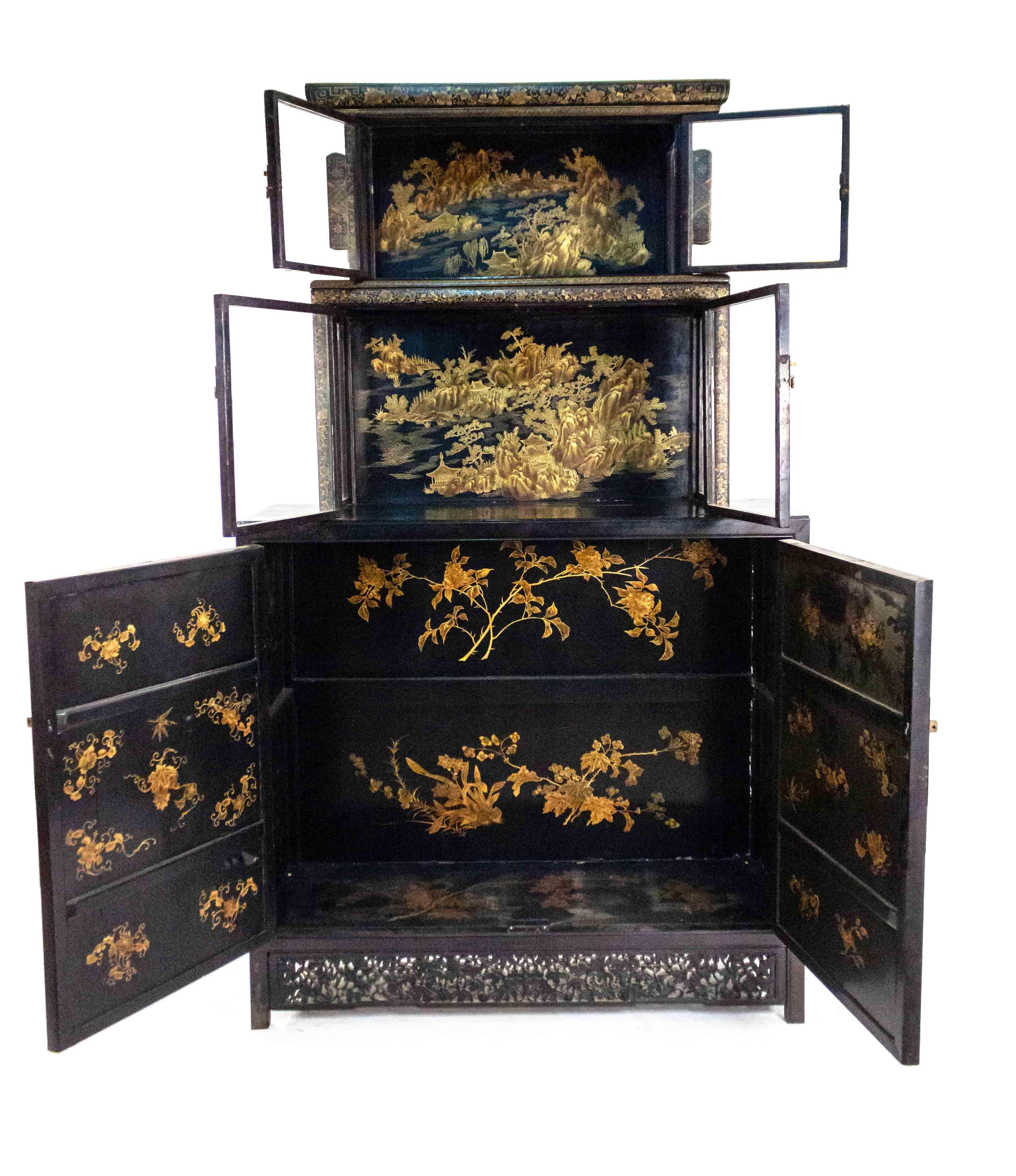 Paire d'armoires chinoises à trois niveaux en verre et en bois laqué noir, décorées de scènes de paysage et de bordures sculptées, avec des ferrures en laiton et un intérieur détaillé (début du 20e siècle).