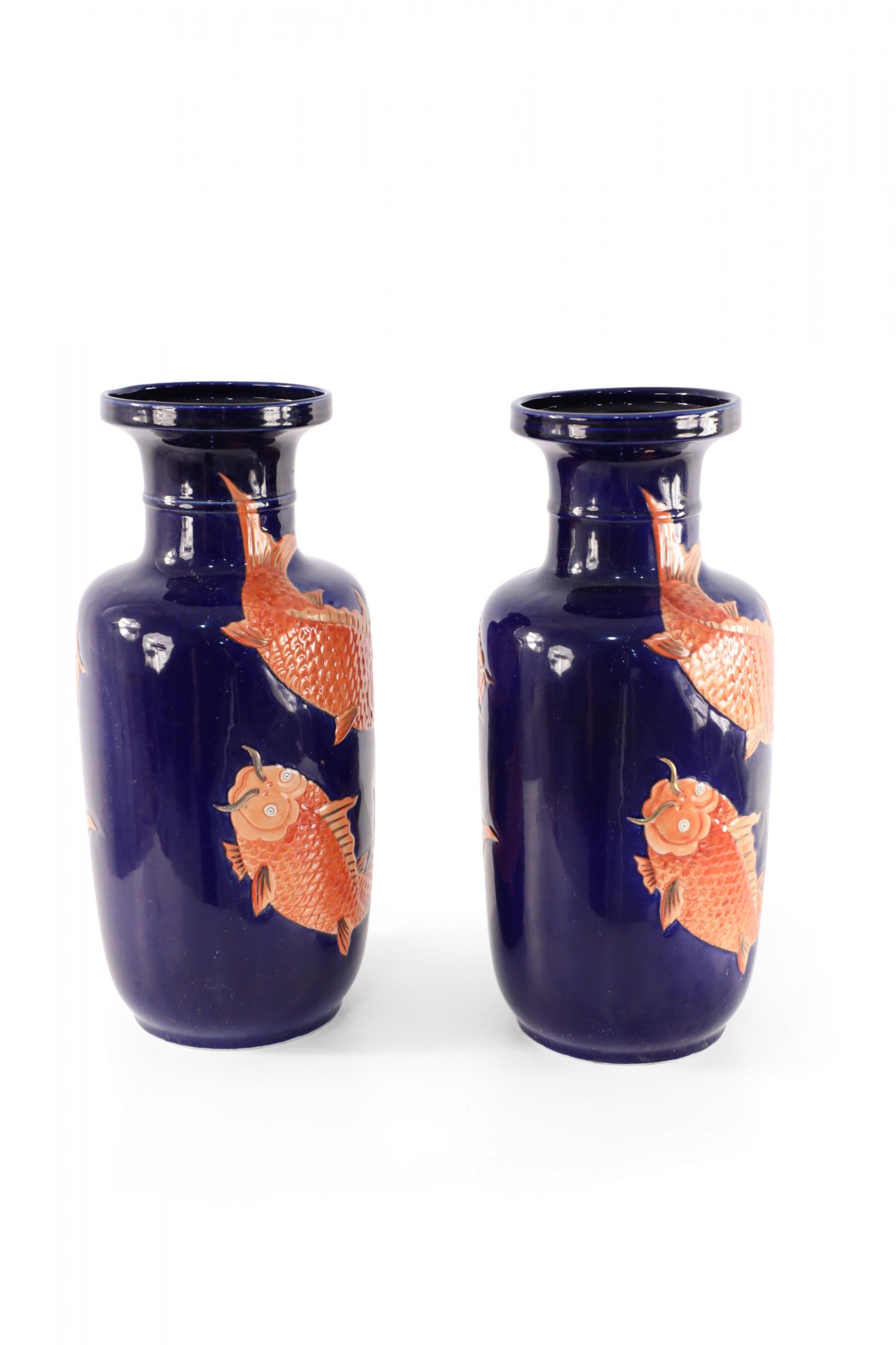 Pair of antique Chinese (mid 20th century) sleeve-shaped porcelain vases decorated with orange fish swimming around blue backgrounds, inspired by patterns from the Ming Dynasty (priced as pair).