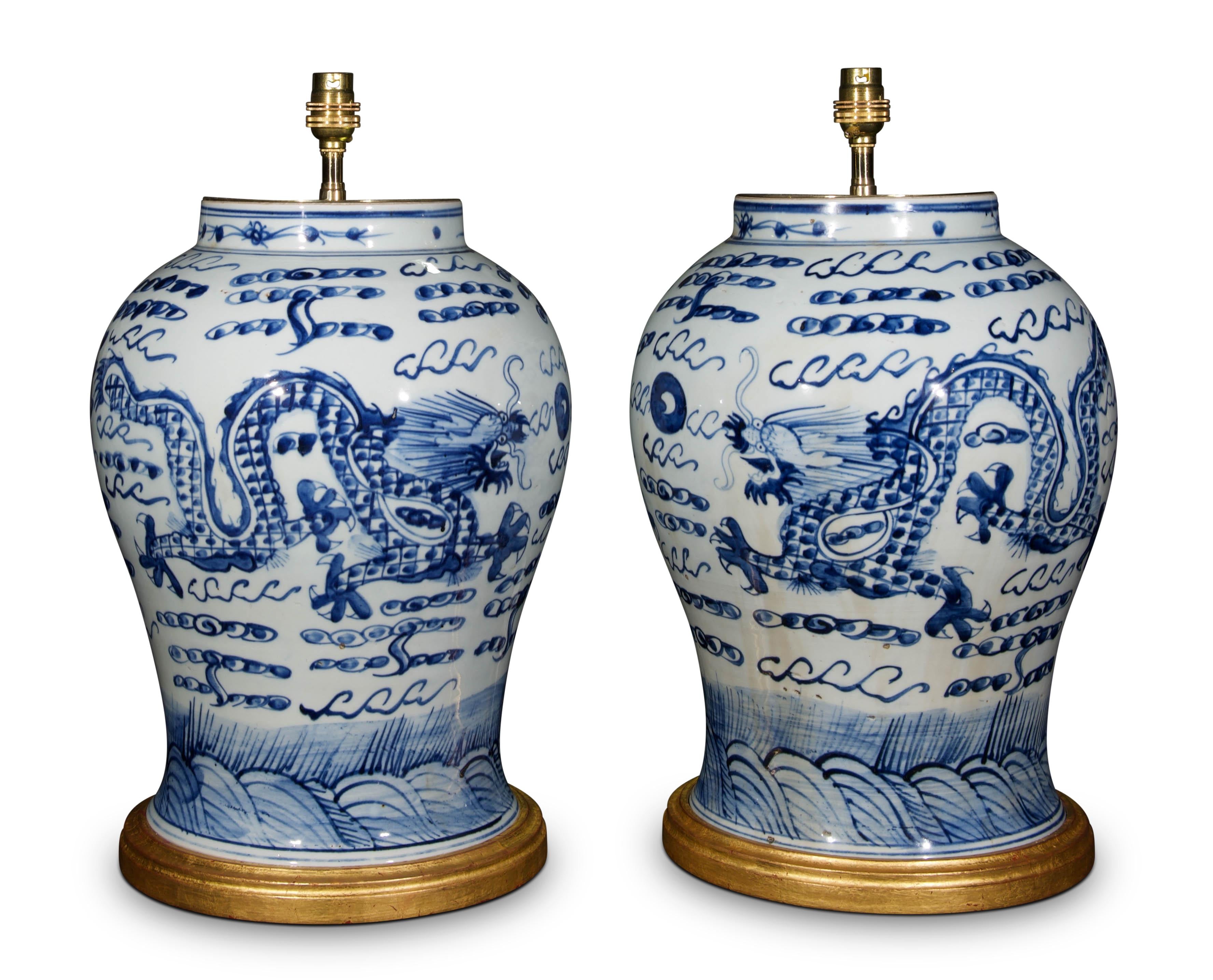 Paire de grands vases balustres chinois en bleu et blanc, décorés dans le style Kangxi, avec des chiens stylisés de Fo dans un paysage feuillu. Ces vases sont maintenant montés comme lampes sur des bases tournées et dorées à la main.

Mesures :