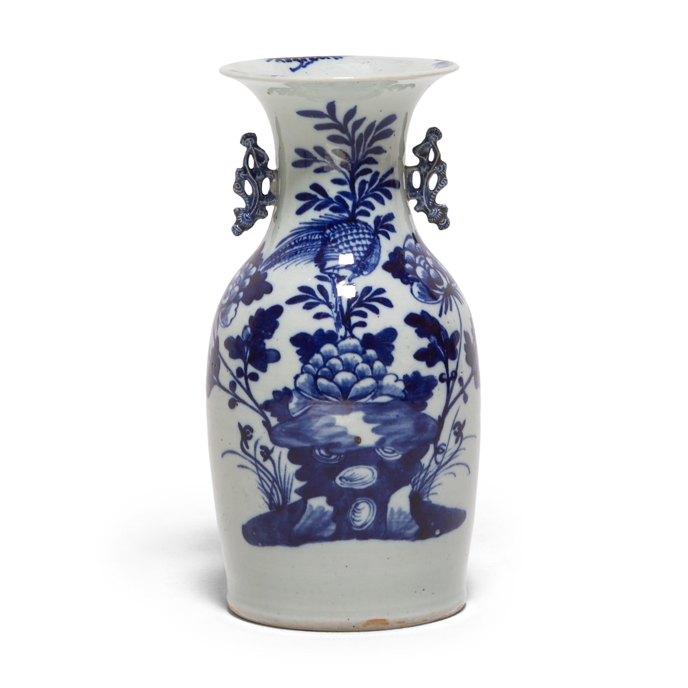 This pair of 19th-century porcelain vases is an exquisite example of blue-and-white pottery. Each vase is expertly formed with thin walls, gently widening to a flared lip, flanked by two molded scroll handles. Painted with richly saturated cobalt