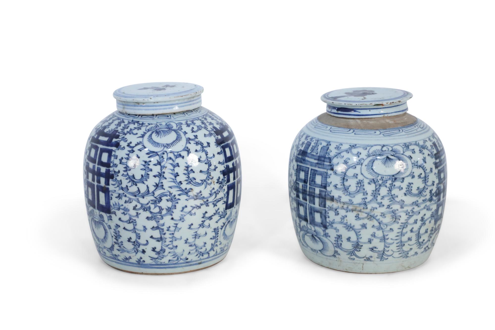 Pair of antique Chinese (late 19th century) similar ceramic ginger jars with blue floral designs surrounding bold, centered characters and geometric patterned bands leading to brown rustic stripes at the mouth openings. Each is topped with a lid