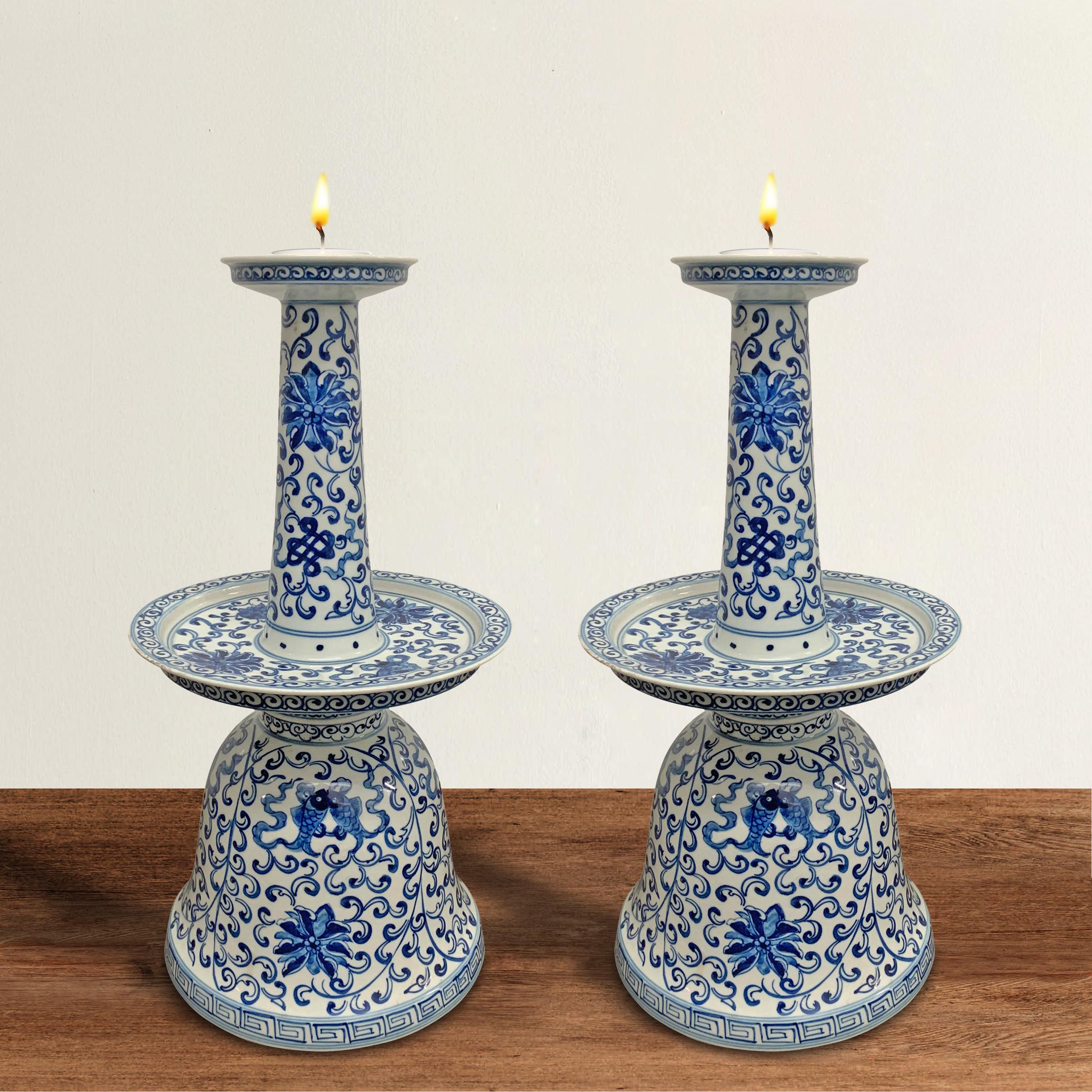 A pair of substantial 20th century Chinese blue and white glazed and hand painted porcelain oil lamps each decorated with the eight auspicious Buddhist symbols including endless knots, double fish, lotus, treasure vases, conch shells, golden wheels,