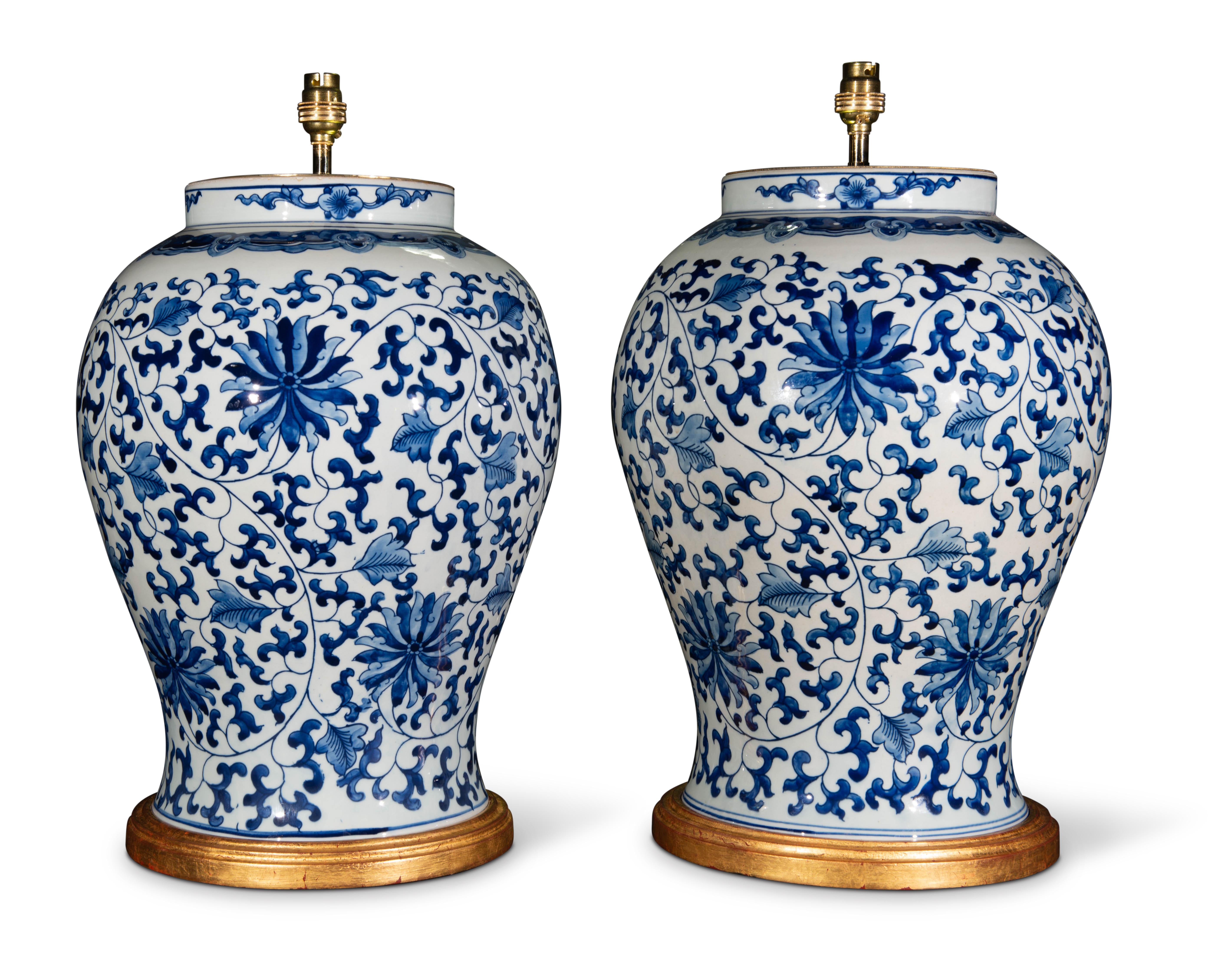 A very fine pair of large Chinese blue and white baluster vases, decorated throughout in the Kangxi style with lotus flowers and trailing foliage in tones of blue on a white ground. Now mounted as lamps with hand gilded turned bases.

Height of