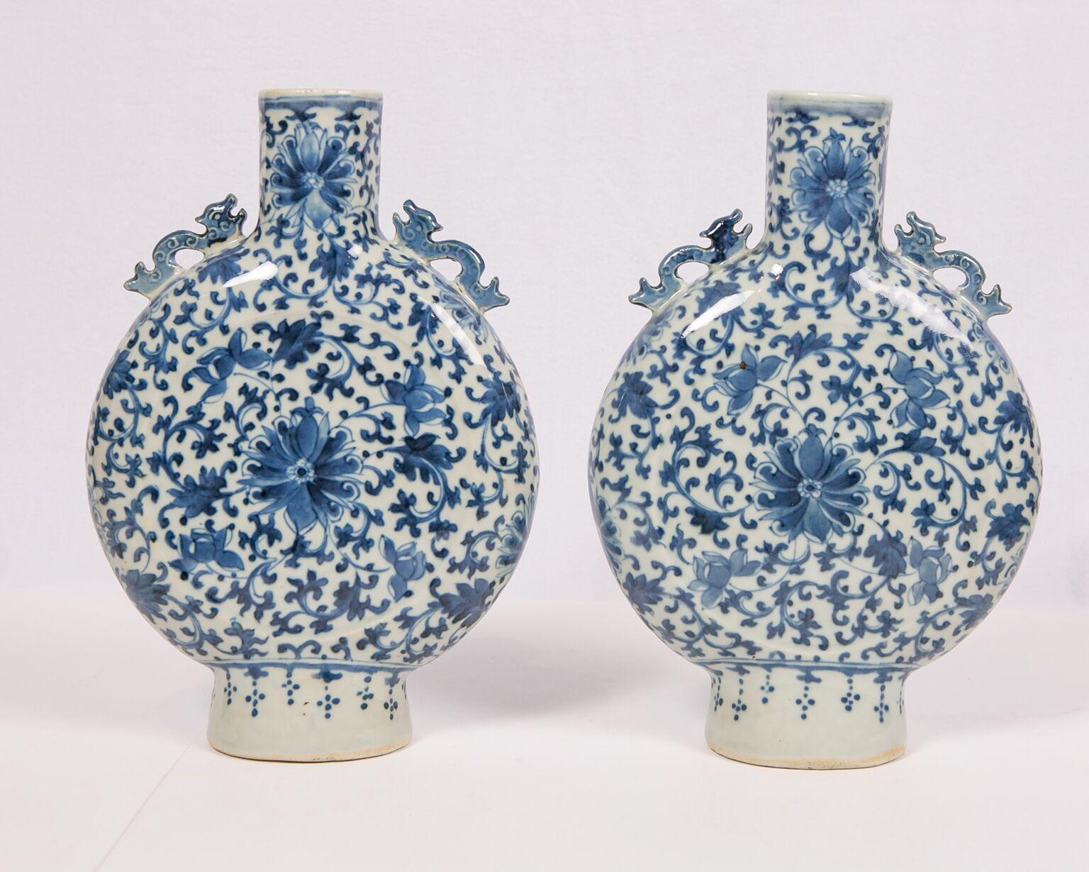 This pair of Chinese blue and w0hite moon flasks date to the 19th century of the Qing dynasty (1644-1911). The body of each vase is fully decorated with floral scroll patterns, executed in a freehand and vibrant style. The flower design in the