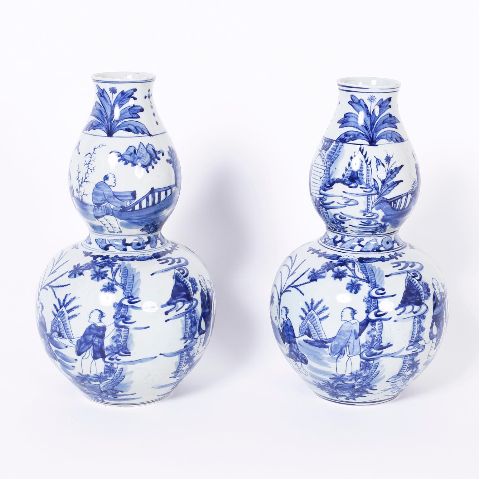 Charming pair of Chinese blue and white porcelain vases with a Classic double gourd form, hand decorated with figures in landscapes.