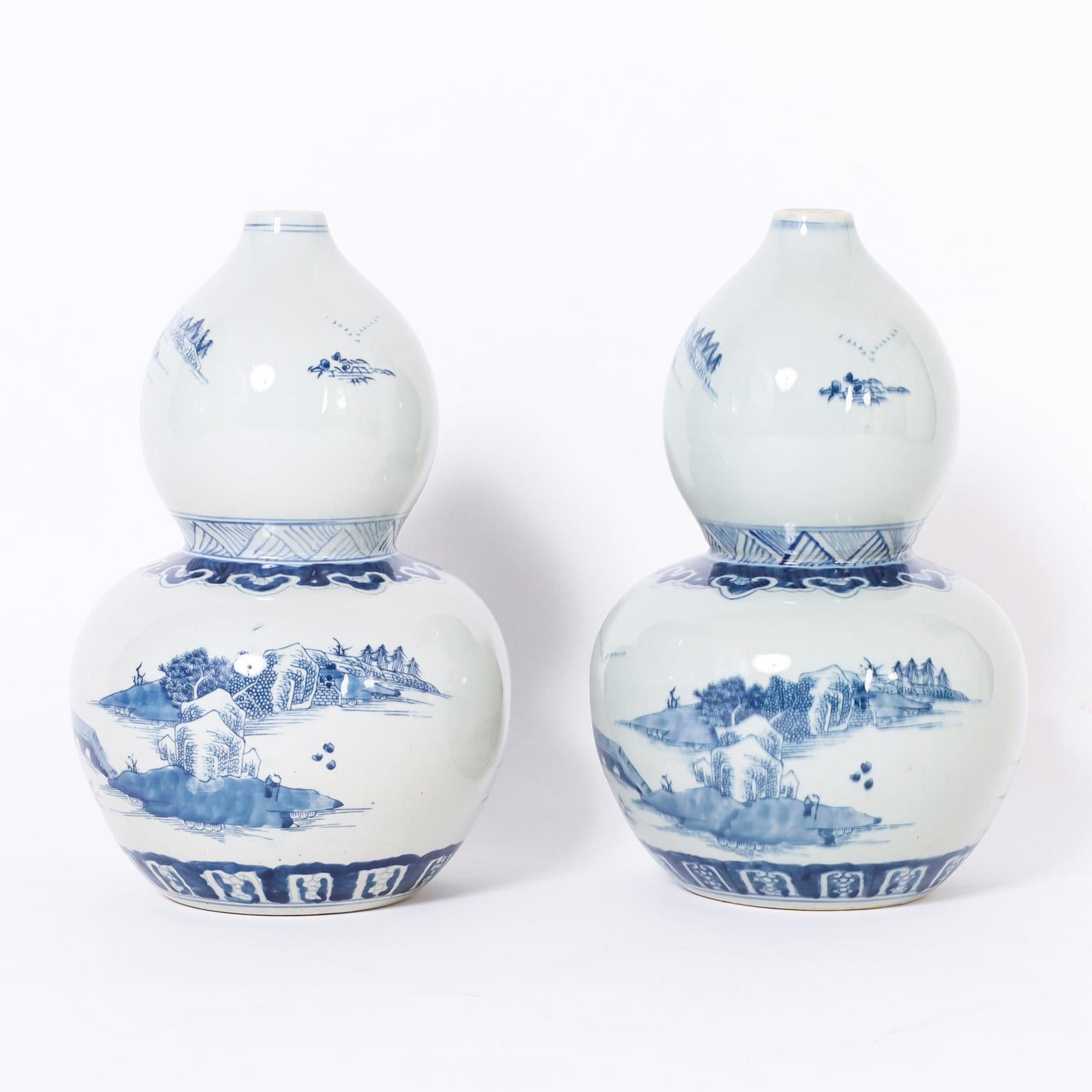 Standout pair of Chinese blue and white porcelain vases having a double gourd form, hand decorated with pagoda landscapes.