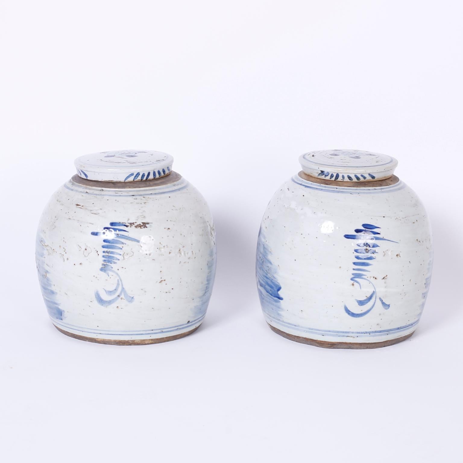Pair of Chinese export style blue and white porcelain ginger jars having a classic bulb form with removable lids and decorated with charming birds and flowers on the fronts.