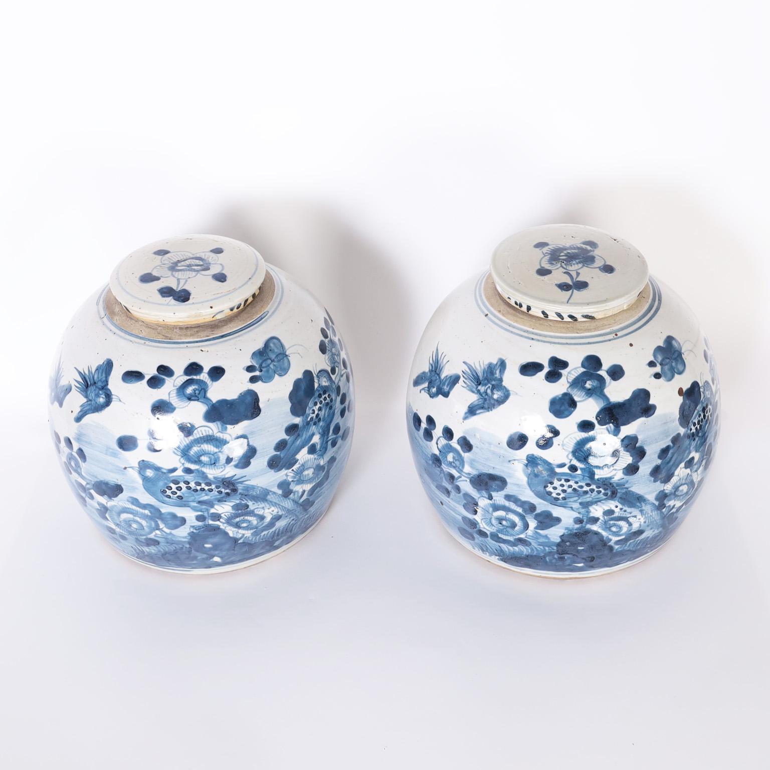 Pair of Chinese blue and white porcelain lidded jars with bulbous form hand decorated with birds and flowers.