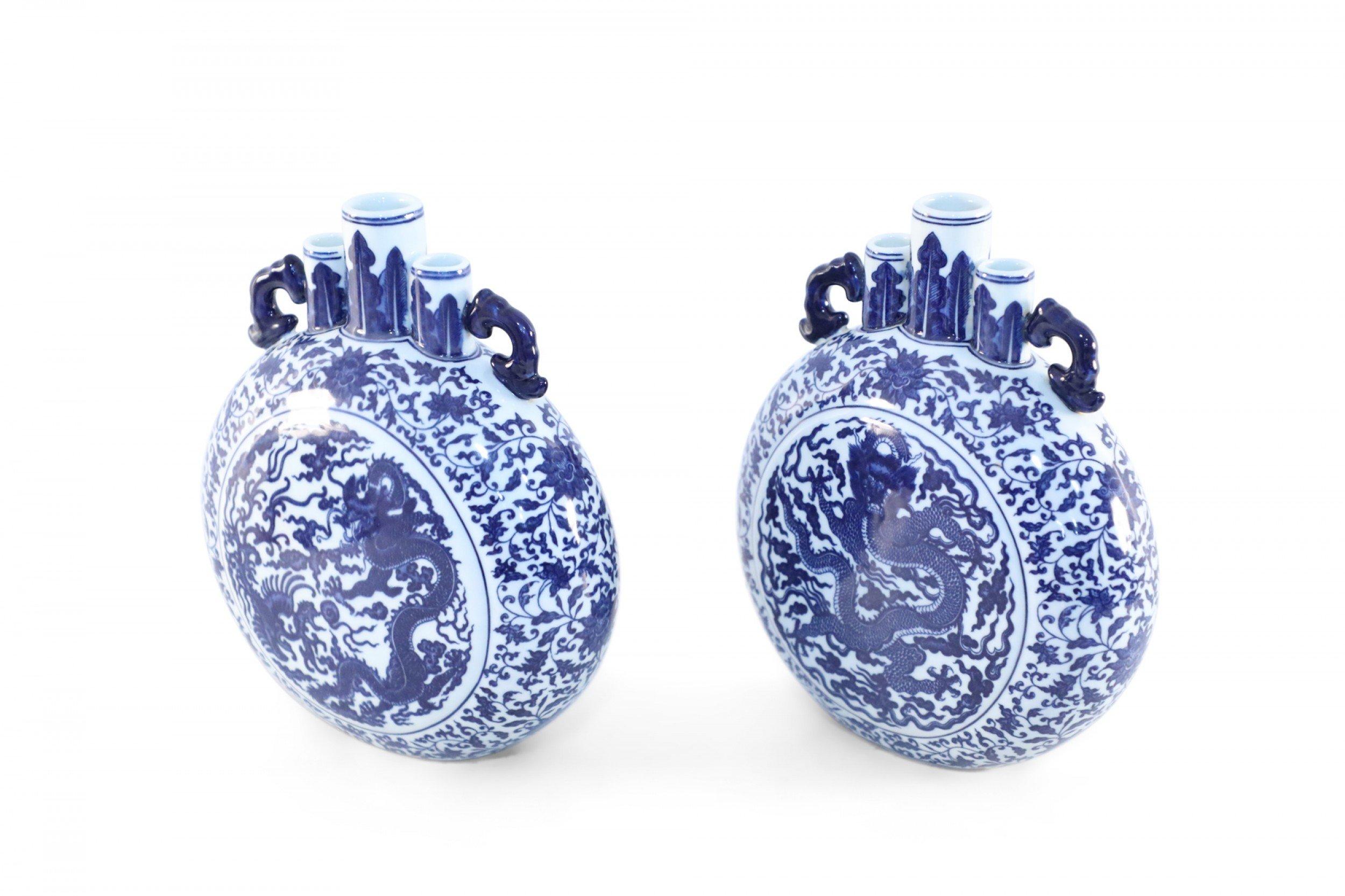 Pair of antique Chinese (Late 19th century) blue and white porcelain moon flask vases depicting centered dragon motifs surrounded by floral and vine designs, and topped with two blue handles flanking three separate mouth openings (date mark on