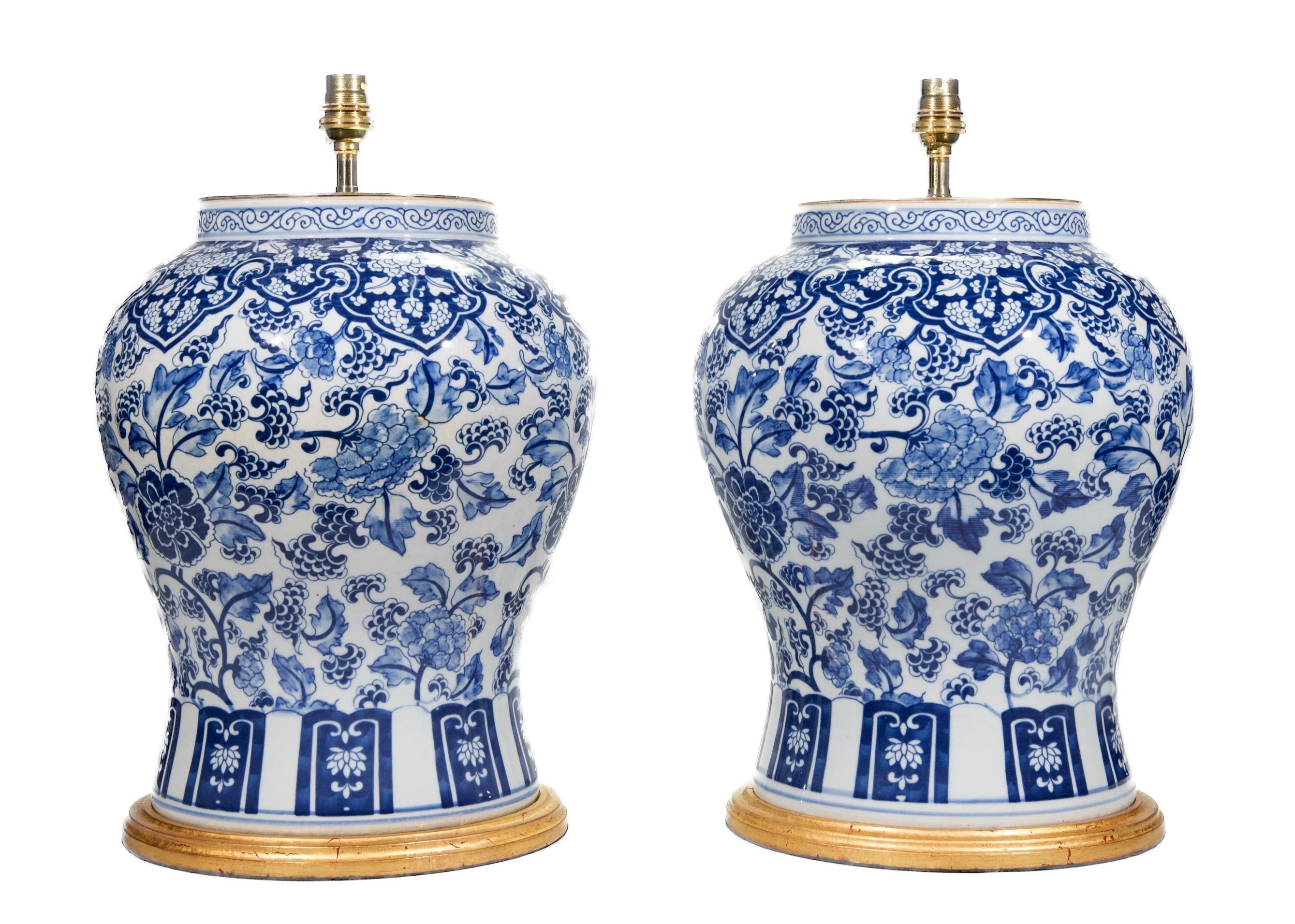 Une belle paire de vases de temple bleus et blancs, décorés à la manière Kangxi de fleurs et de feuillages stylisés dans des tons bleus sur un fond blanc, maintenant montés comme lampes avec des bases dorées à la main.

Hauteur des vases : 14 3/4 in