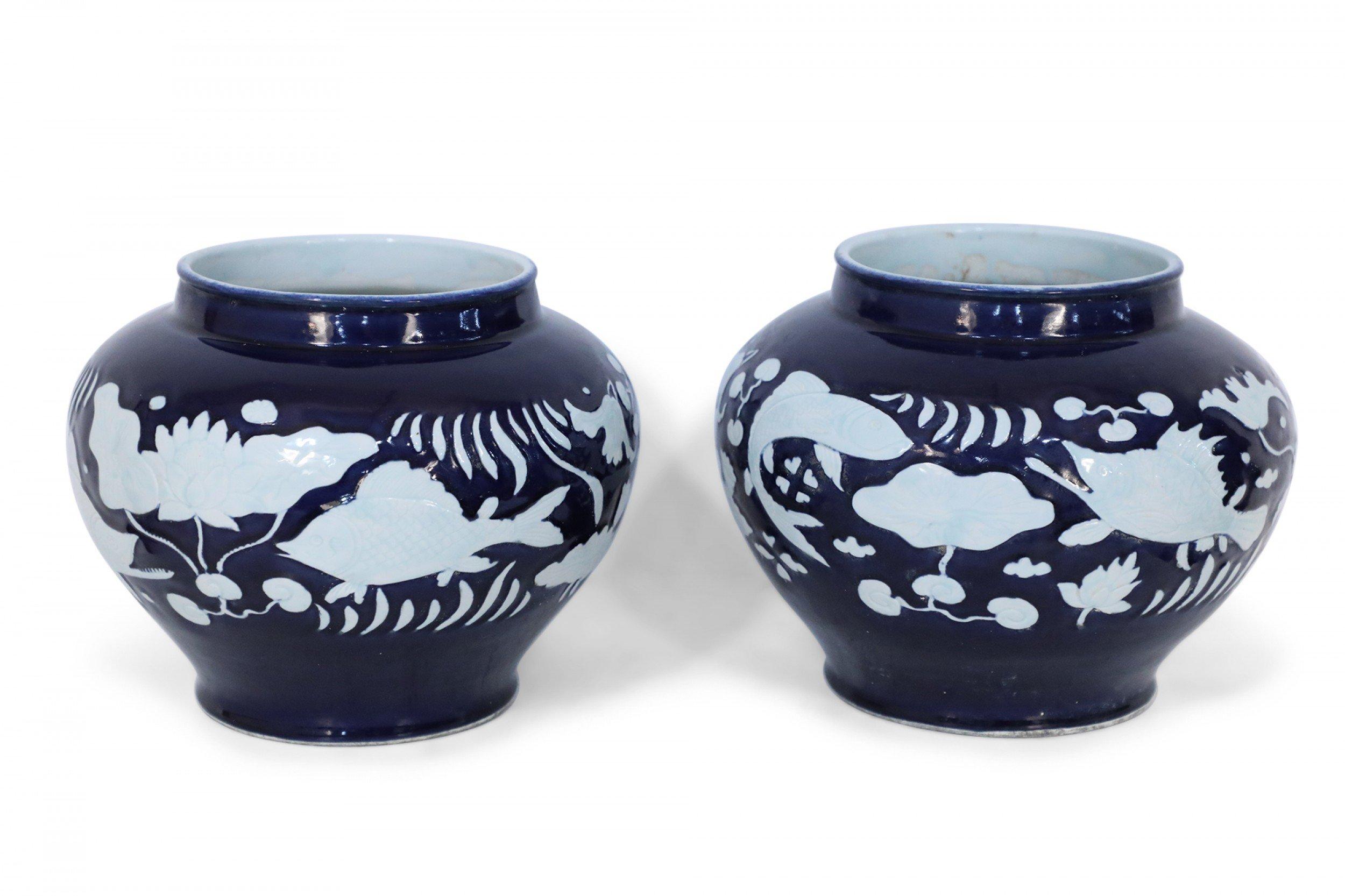 PAIR of Chinese porcelain pots in dark navy hues decorated with white underwater motifs capturing the silhouettes of fish and vegetation (PRICED AS PAIR).