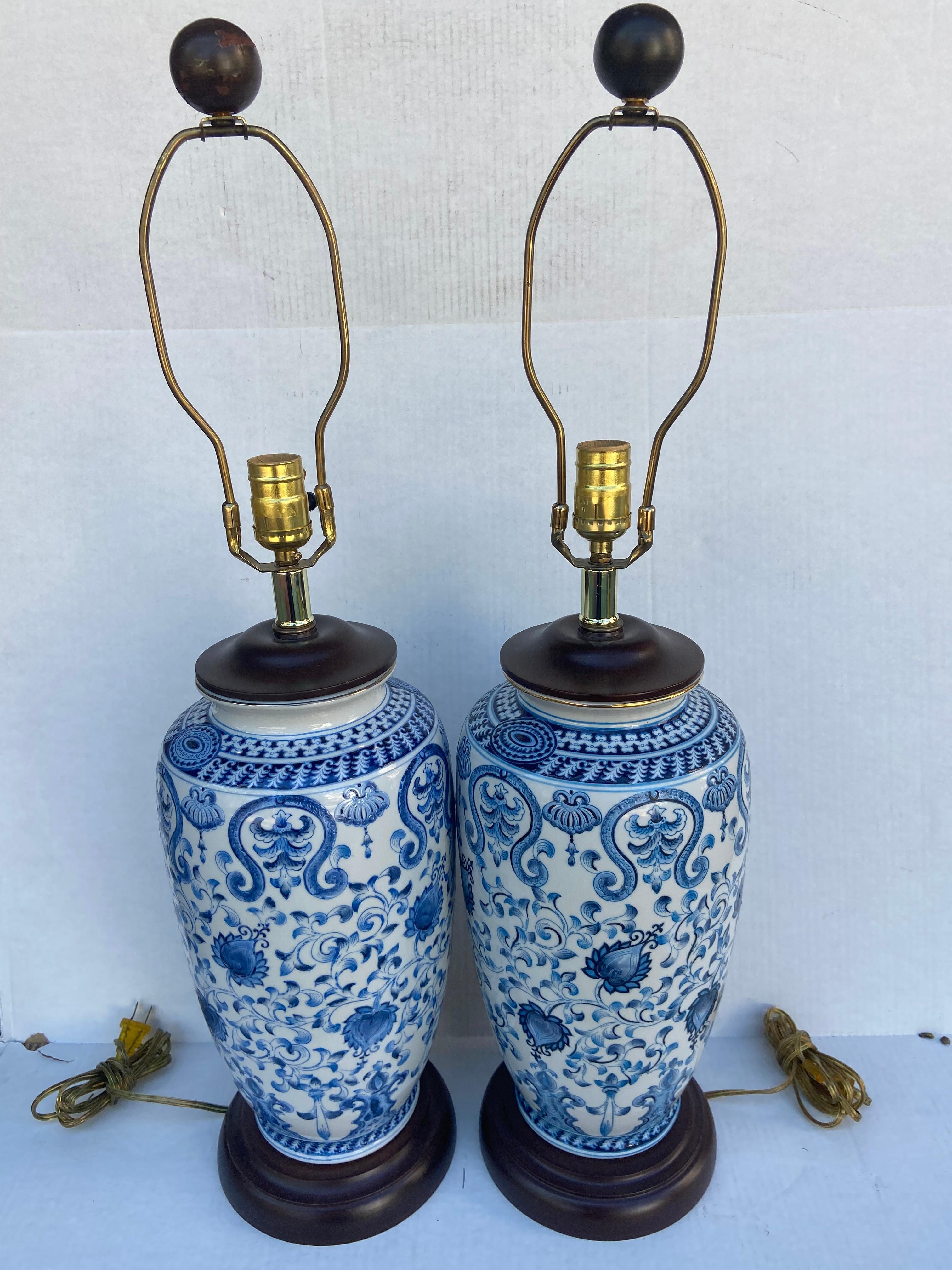 A pair of Chinese blue & white porcelain vases mounted as lamps with wooden tops, bottoms and finals. Top trimmed with a gold. trim. American with a Chinese flare. Beautiful all around floral designs on vases. Came from a prominent New York City