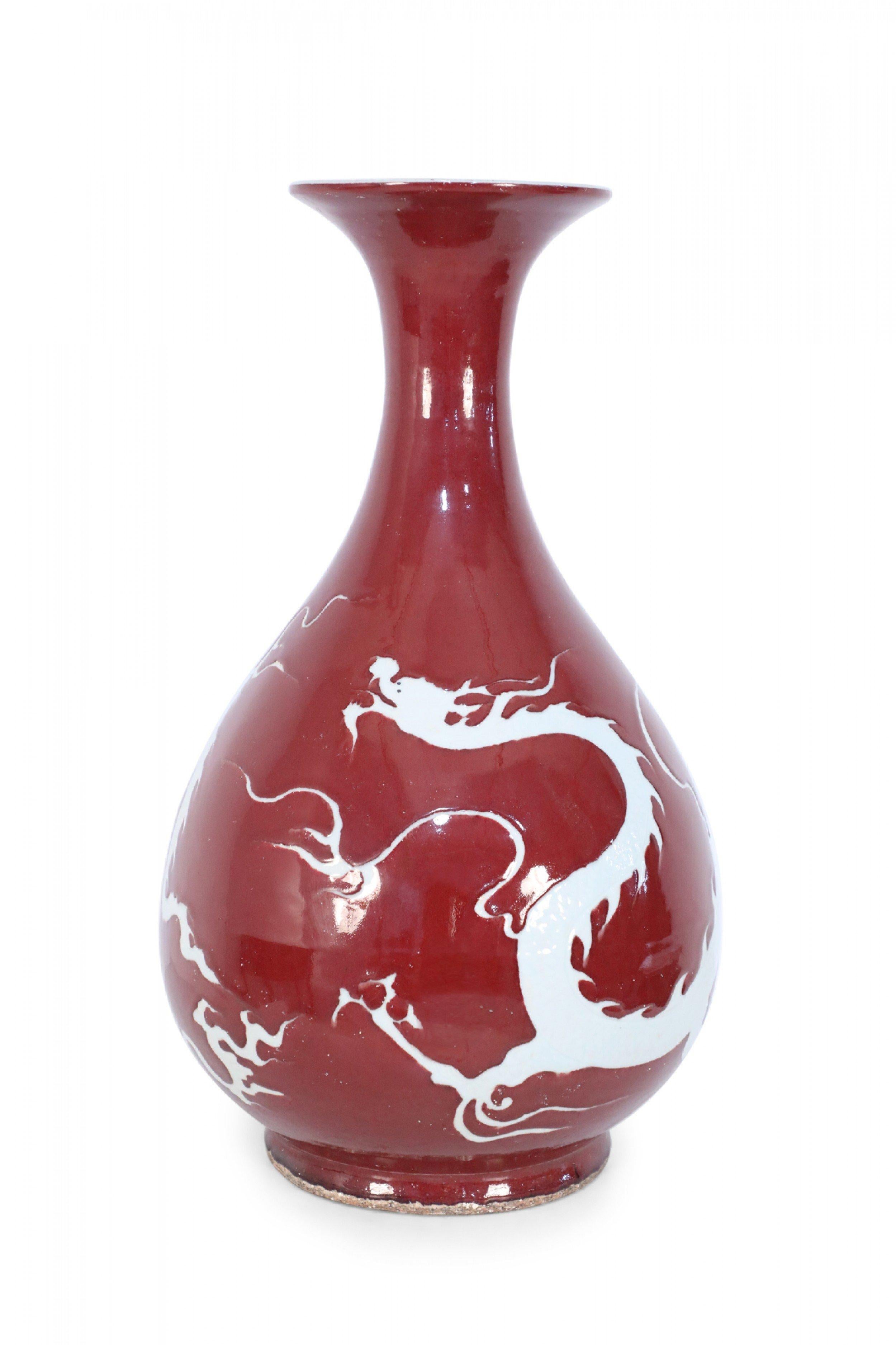 Pair of Chinese ceramic burgundy vases decorated with the white silhouettes of dragons wrapping around their pear-shaped forms (priced as pair).
   