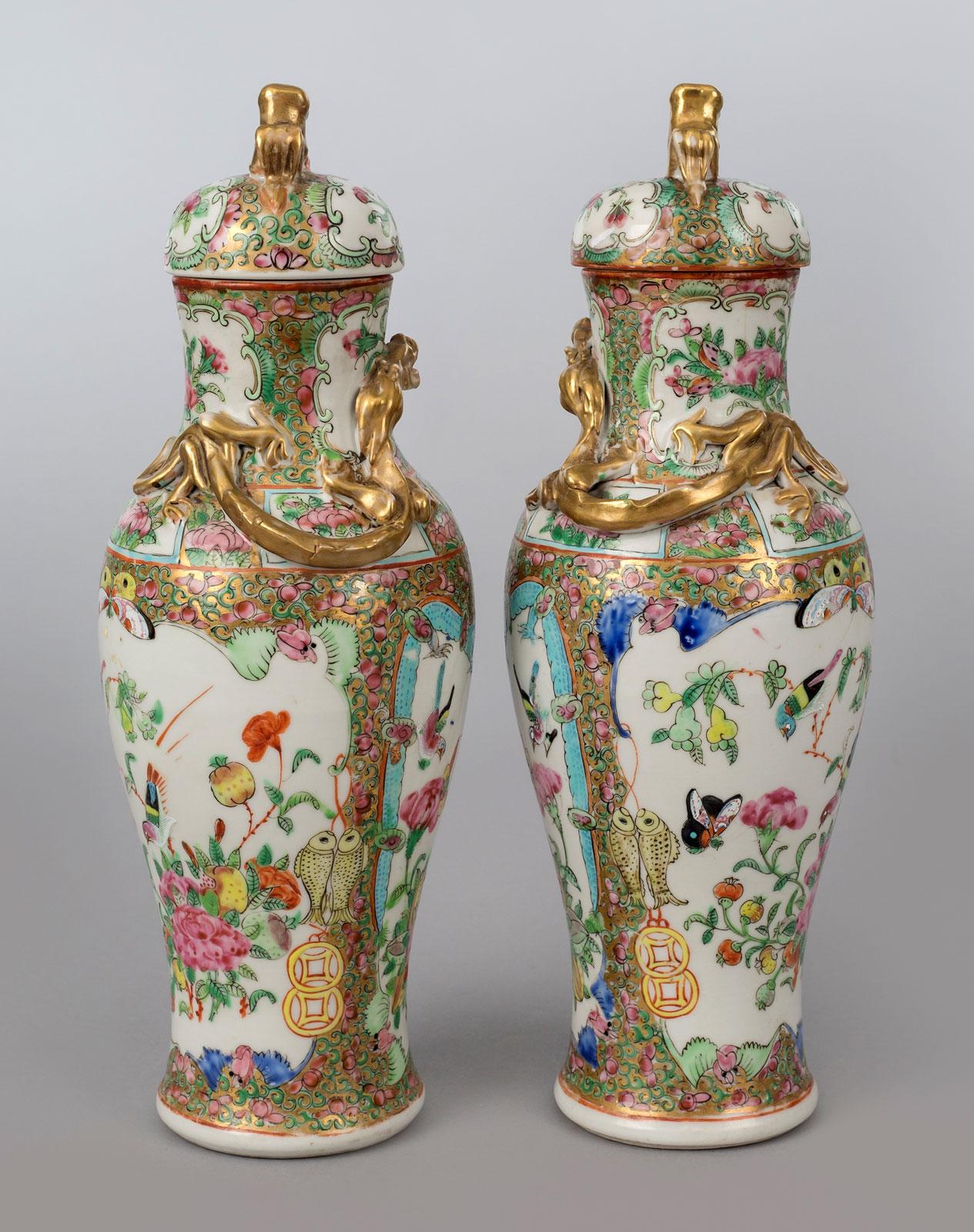 Pair Chinese export Canton porcelain baluster-shaped lidded vases in the famille rose palette, decorated with gilded dragons encircling the neck, the two shield shapes enclosing birds, butterflies, flowers and framed by blue dragons, bats, yellow