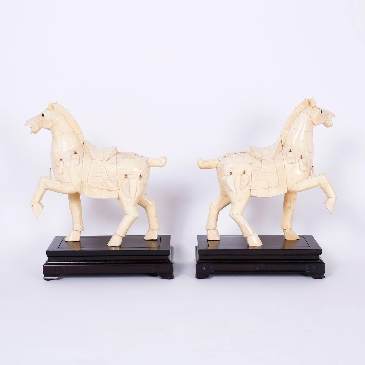 Impressive pair of Chinese carved bone horses with classic Tang dynasty form presented on carved wood ebonized stands.
   