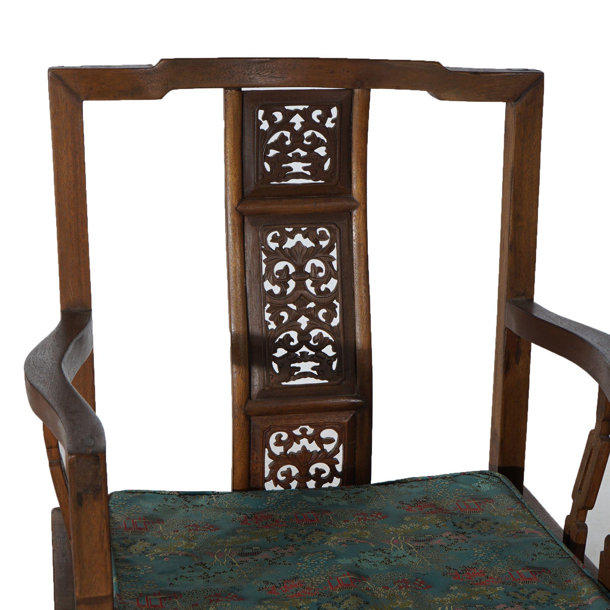 A pair of Chinese throne  arm chairs offer carved hardwood construction with pierced slat backs having foliate elements, silk upholstered cushions, and raised on straight and square legs terminating in stylized hoof feet, mid-20th century

Measures