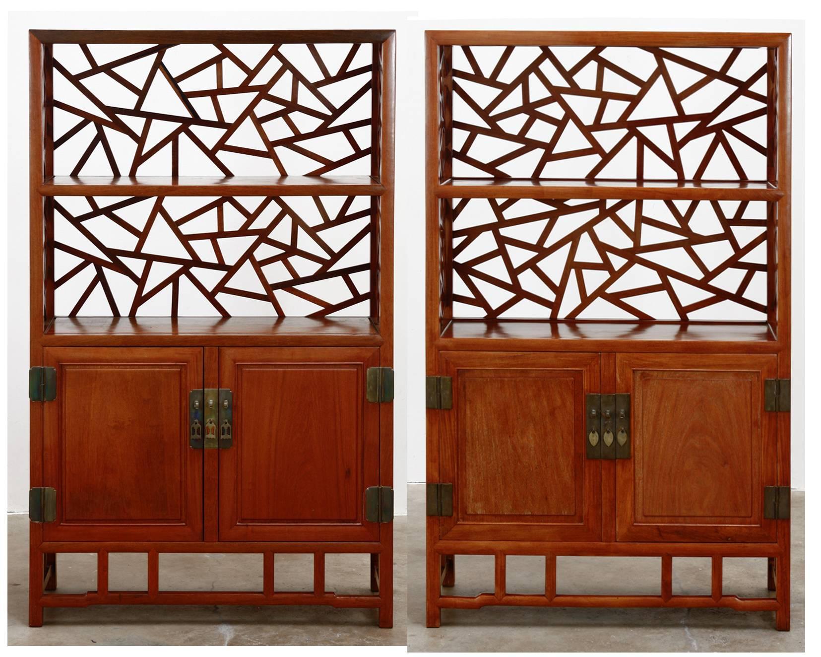 Fantastic pair of Chinese carved rosewood display curio cabinets or bookcases. Featuring a lattice open fretwork design of cracked ice. Intricately carved on three sides having two open shelves on top and two shelves inside the storage area. Solid