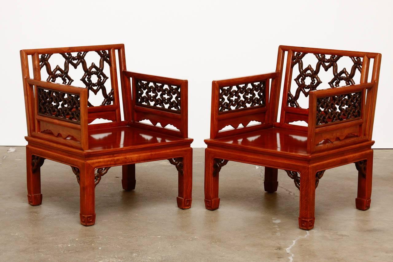Exceptional pair of Chinese carved lounge chairs or armchairs. Constructed from radiant grain Huali rosewood. Intricate pierced open fretwork design on the back and arm inserts featuring and amazing degree of craftsmanship. The floating seats are