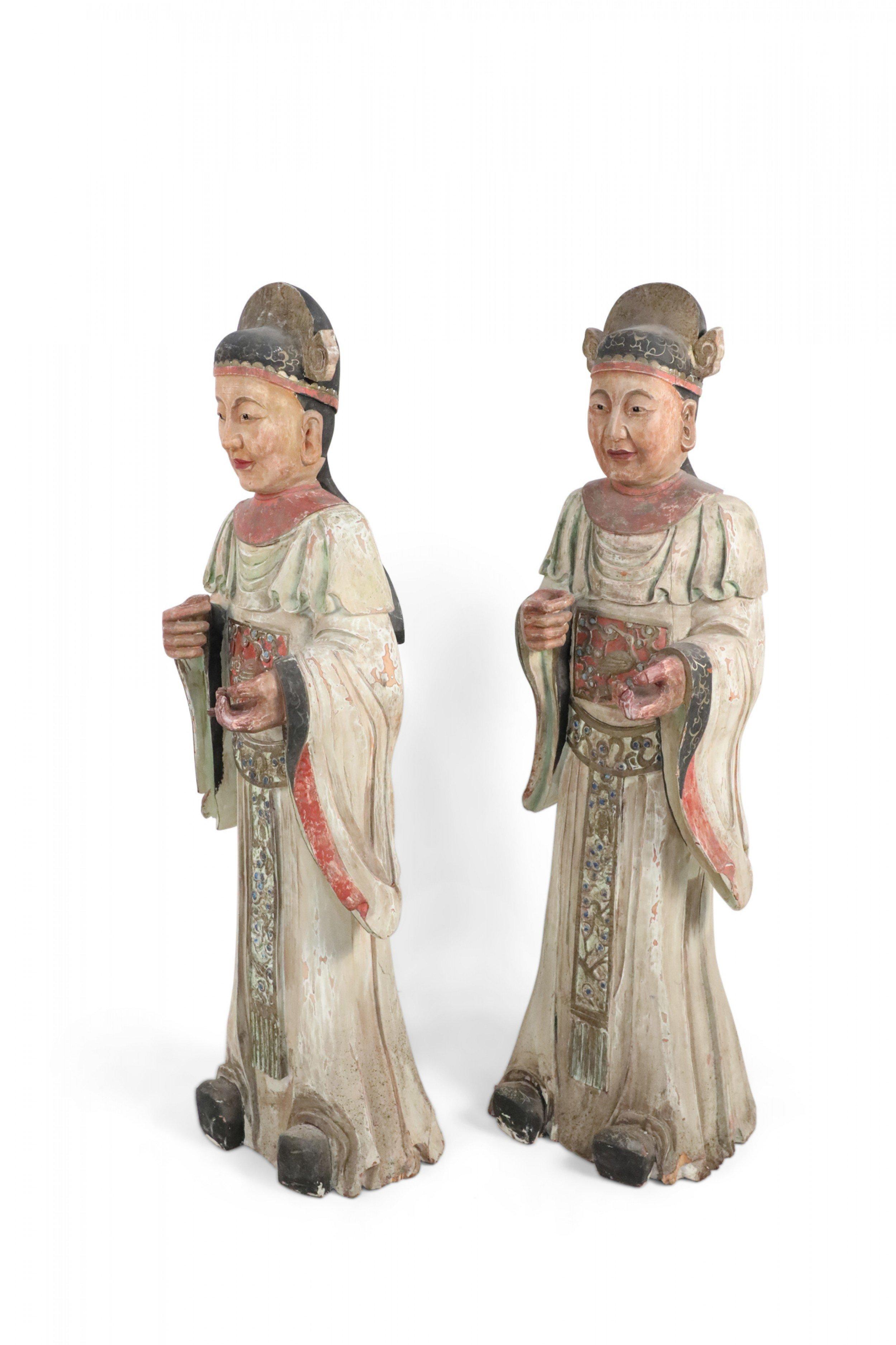 2 chinesische geschnitzte Holzstatuen von Zivilbeamten, die weiße Gewänder mit roter Verzierung, eine rote breite Schärpe über dem Ausschnitt und einen verzierten Gürtel unter dem Ausschnitt tragen (je Preis).
  